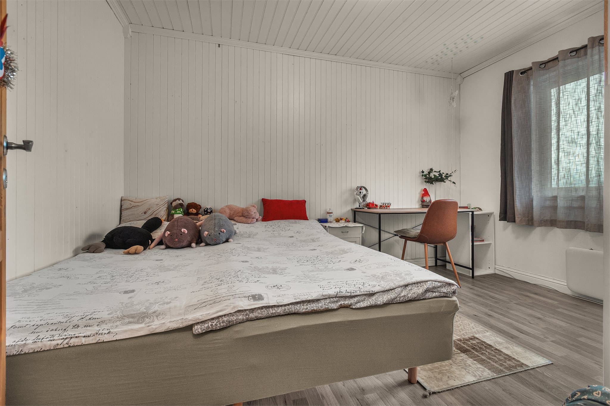 Soverom i andre etasje med lyst panel på vegger og god plass til dobbeltseng.
