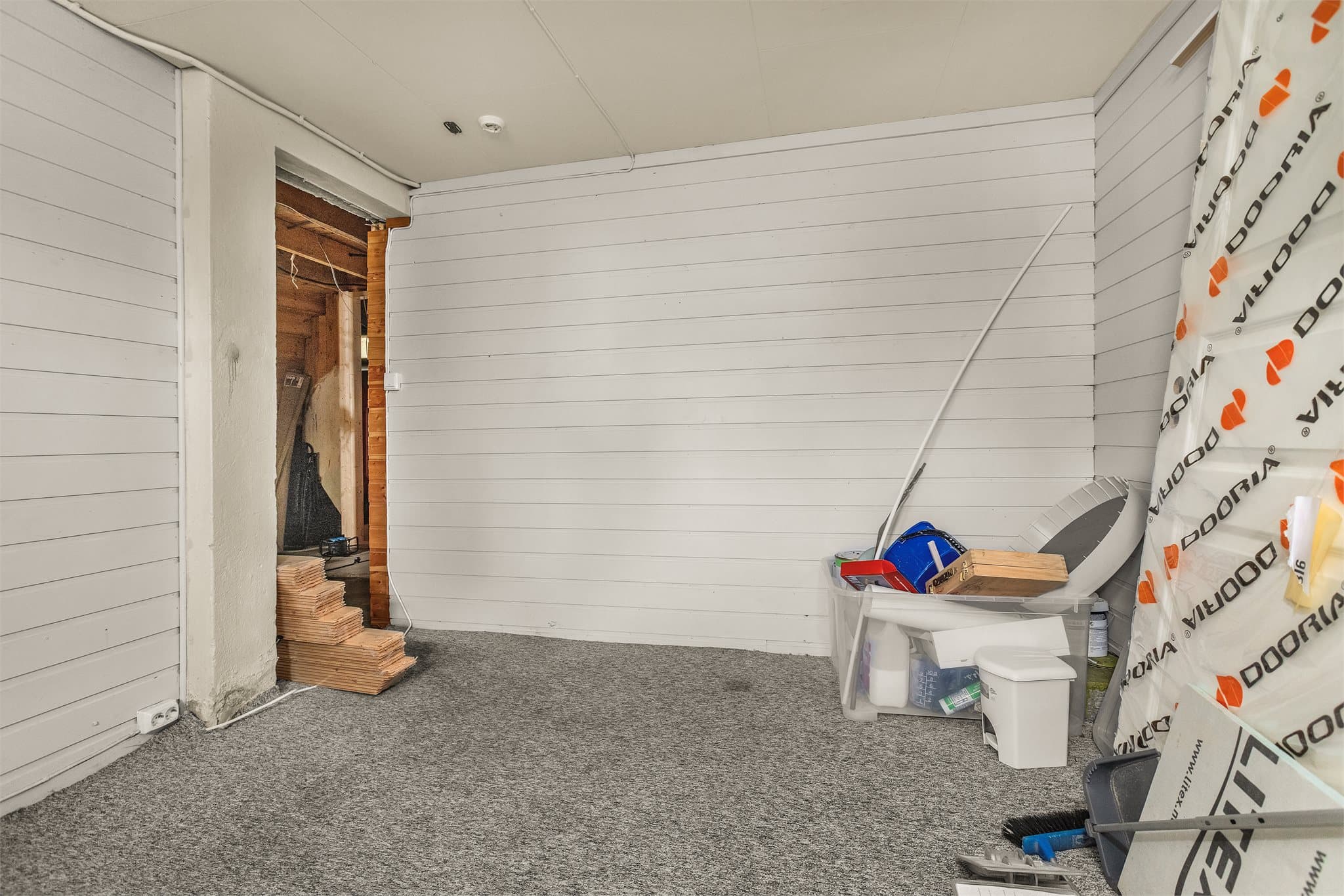 Rom i kjeller med hvitmalt panel på veggene.