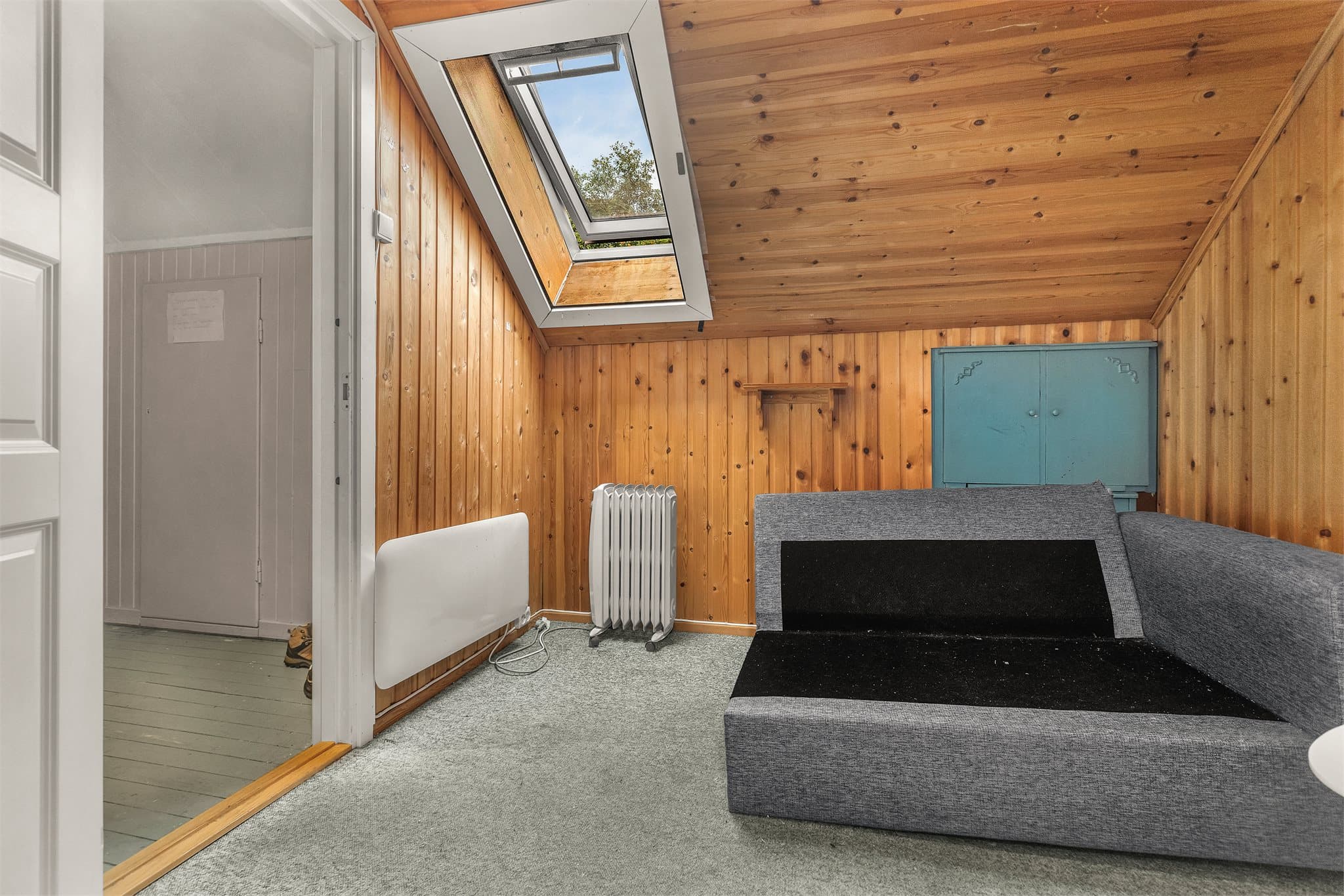 Innredet rom på loftet med panelte overflater og takvindu fra 2015.