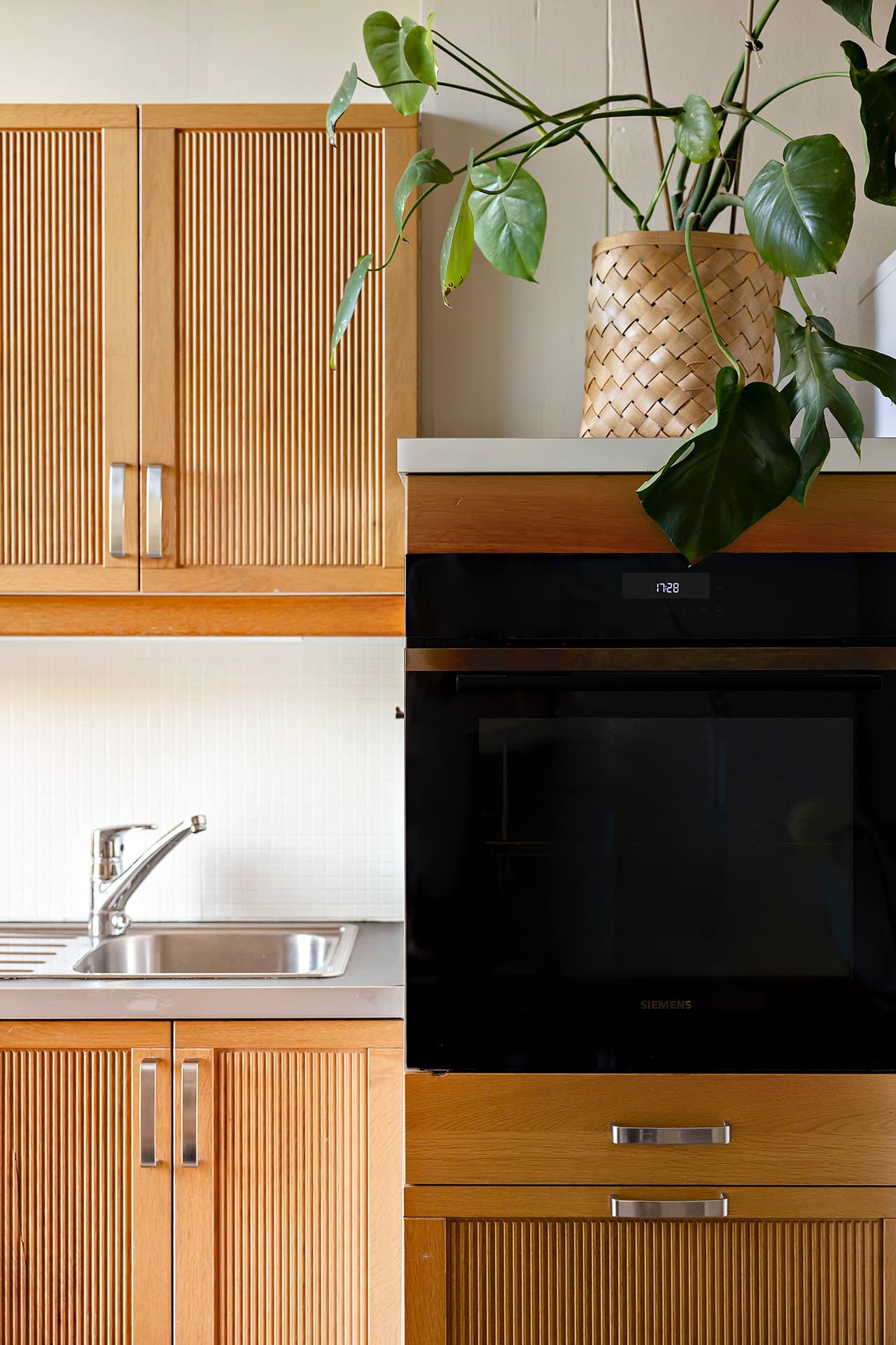 Kjøkkeninnredningen har elegante, heltre fronter med profil, og benkeplaten i laminat er utstyrt med nedfelt kum i rustfritt stål.