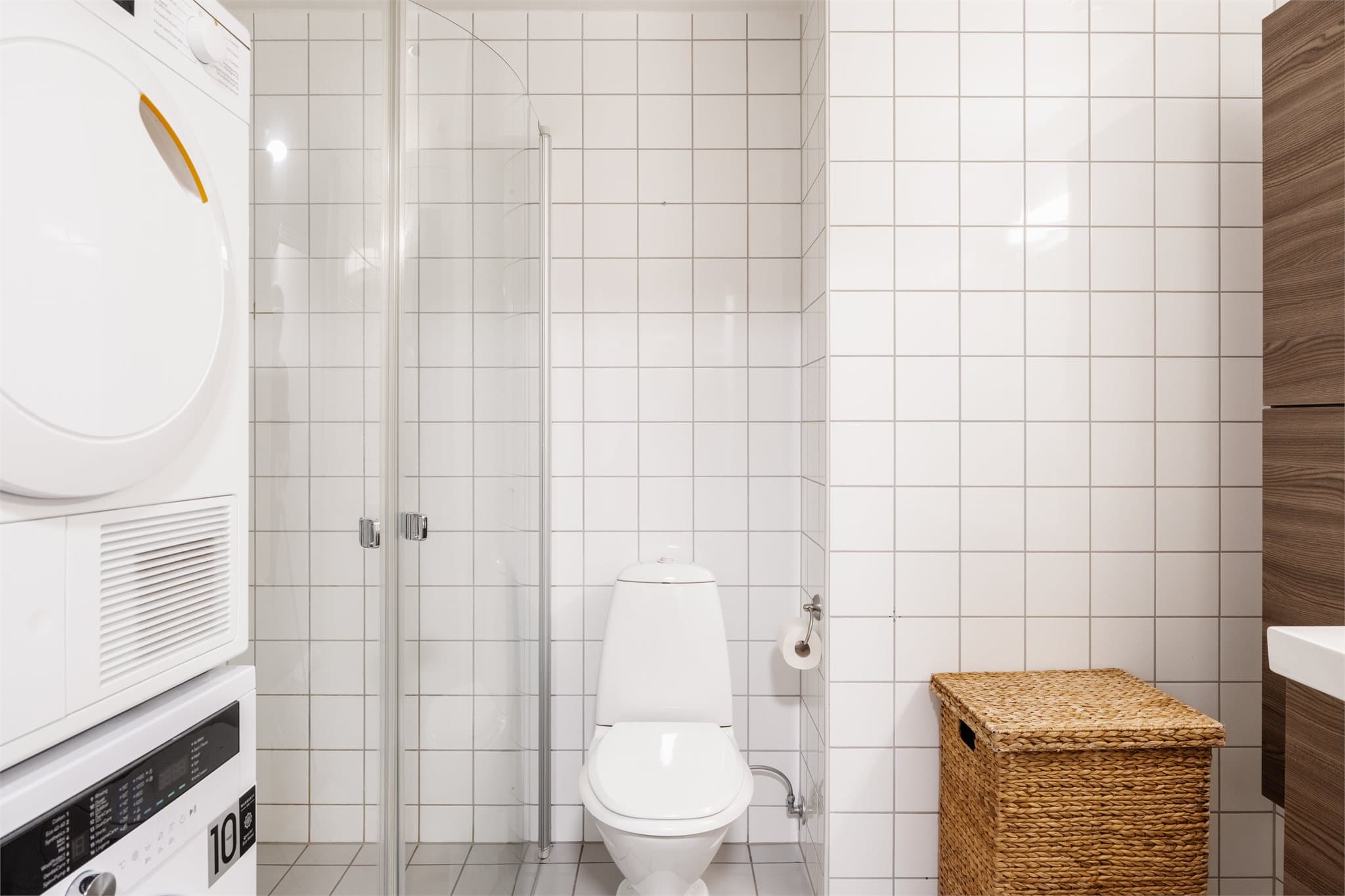 Badet har dusjhjørne med innfellbare dører og opplegg for vaskemaskin.