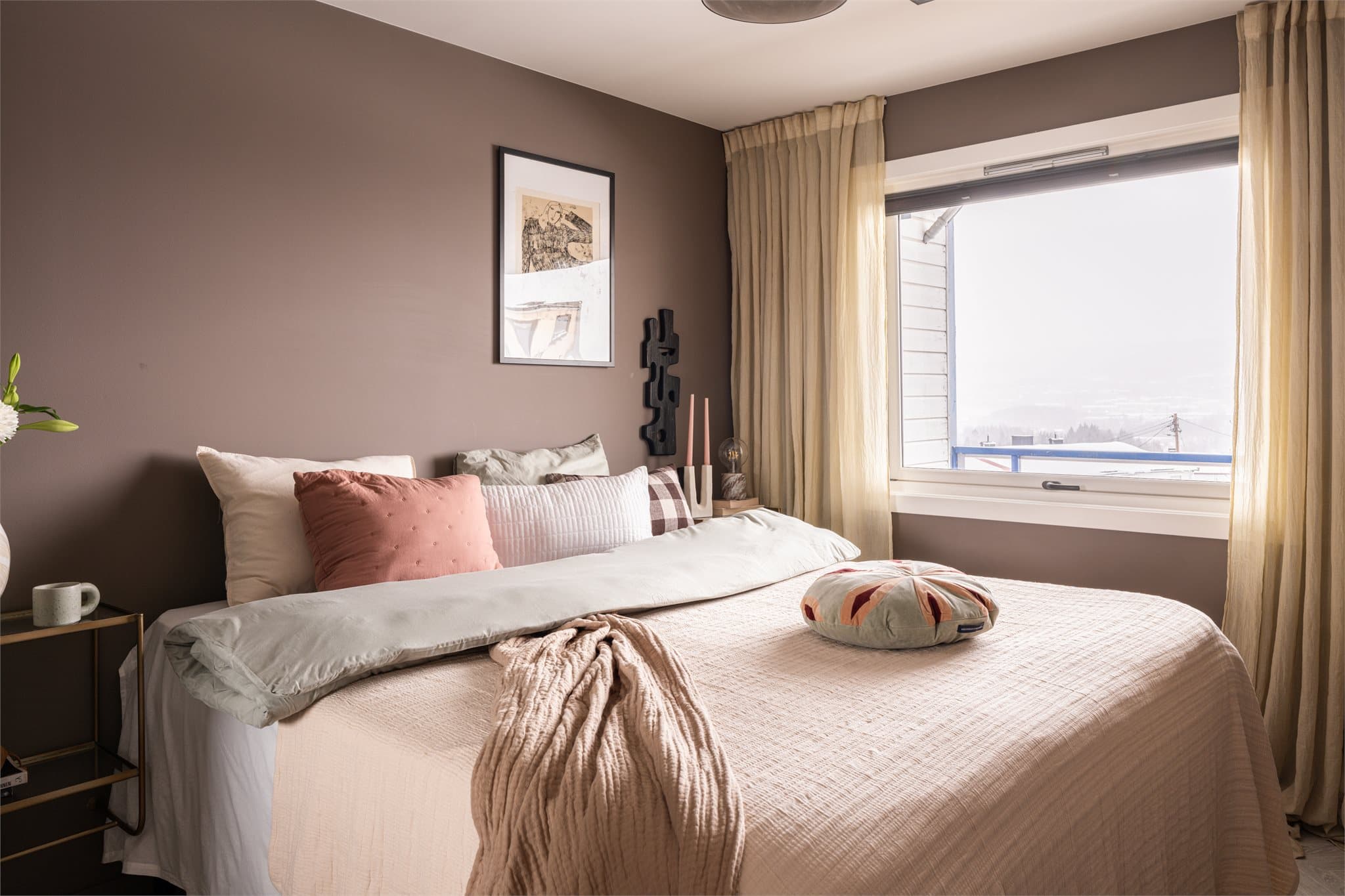 Et innbydende soverom med mye naturlig lys fra det store vinduet.
