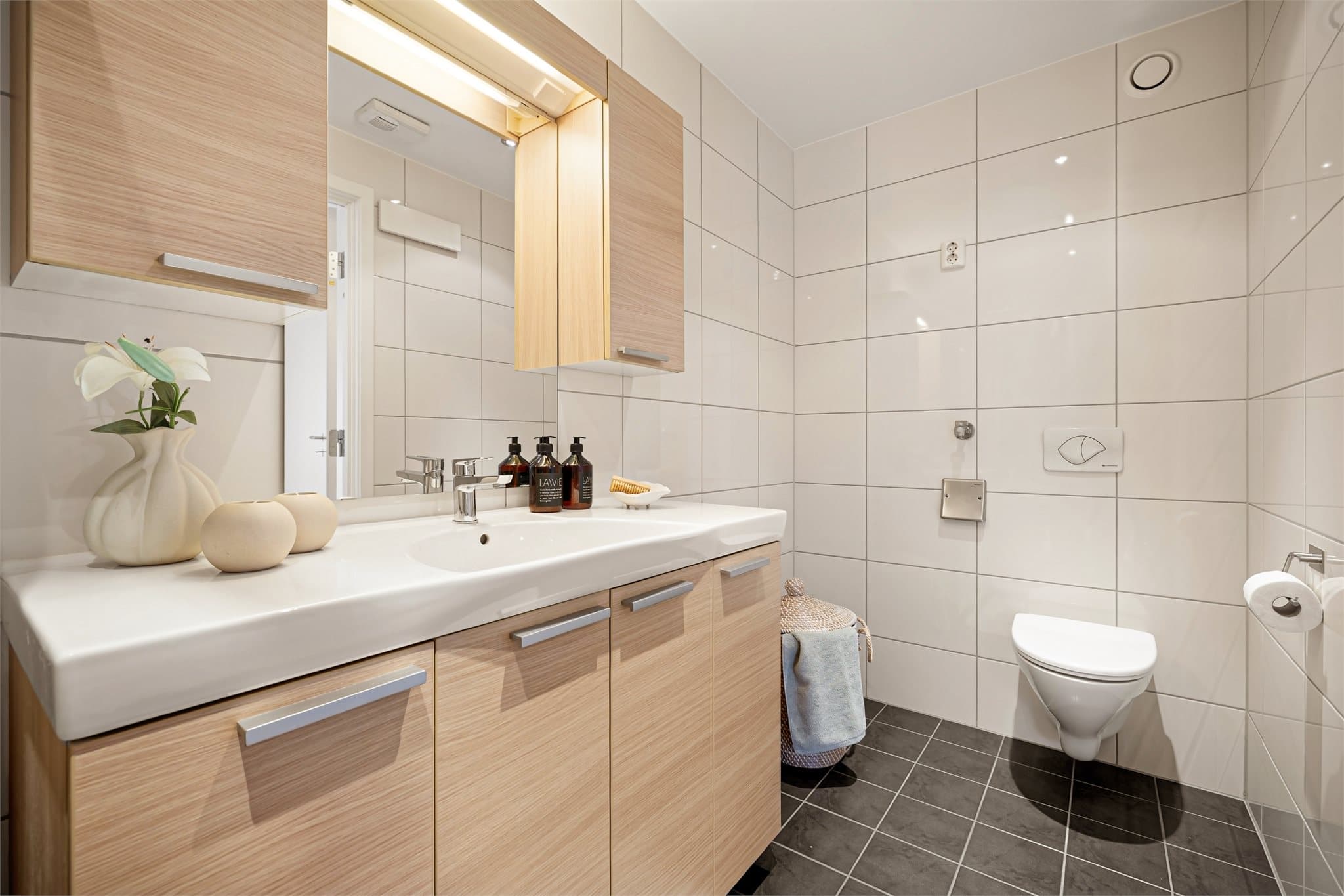 Badet følger kjøkkenets stil med trefarget baderomsinnredning og skaper et gjennomført helhetsinntrykk. Badet har nylig fått montert nytt dusjarmatur og nytt blandebatteri.