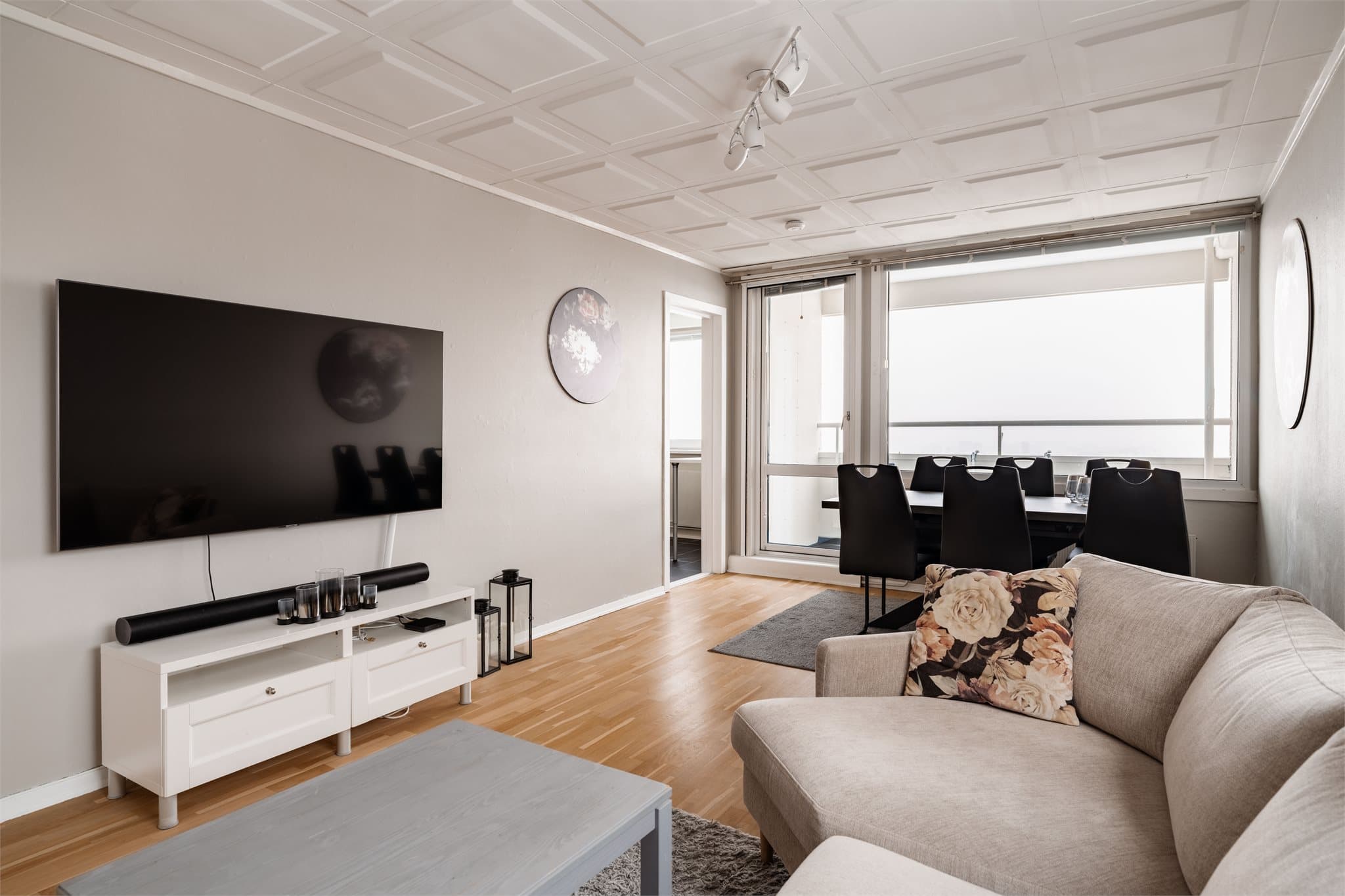 Romslig og lys stue med rikelig lysinnslipp fra vinduer på både ende- og sidevegg.