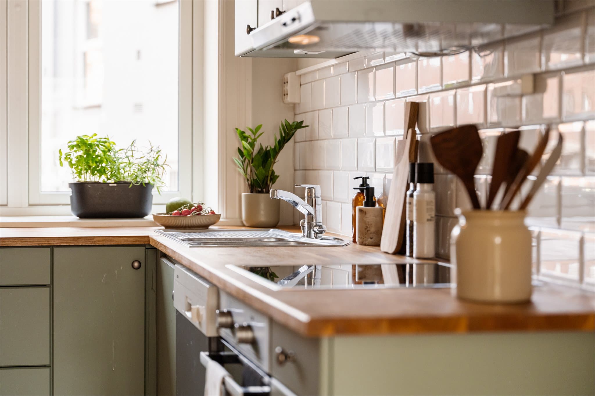 Innredningen fremstår med klassiske, profilerte fronter og benkeplate i tre. Veggen mellom benk og overskap er flislagt, noe som gir en funksjonell og rengjøringsvennlig løsning.