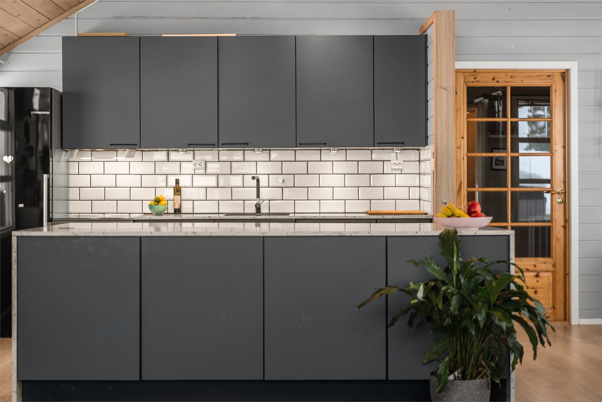Stilrent og moderne kjøkken med flis over benk.