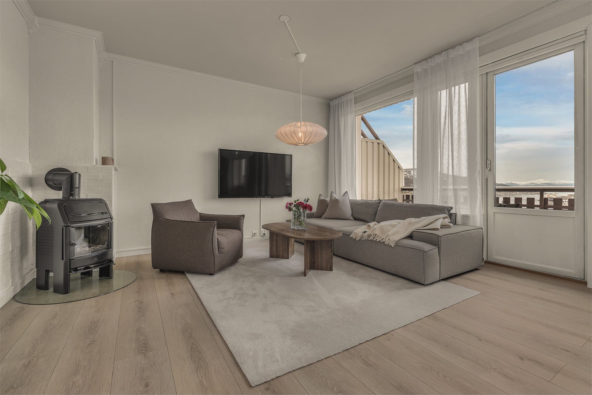 Stuen har store vinduer og koselig vedfyring