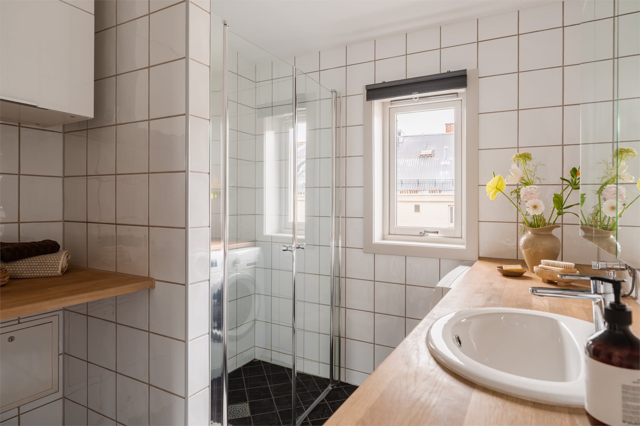 Romslig dusjnisje bak innfellbare dører i glass.