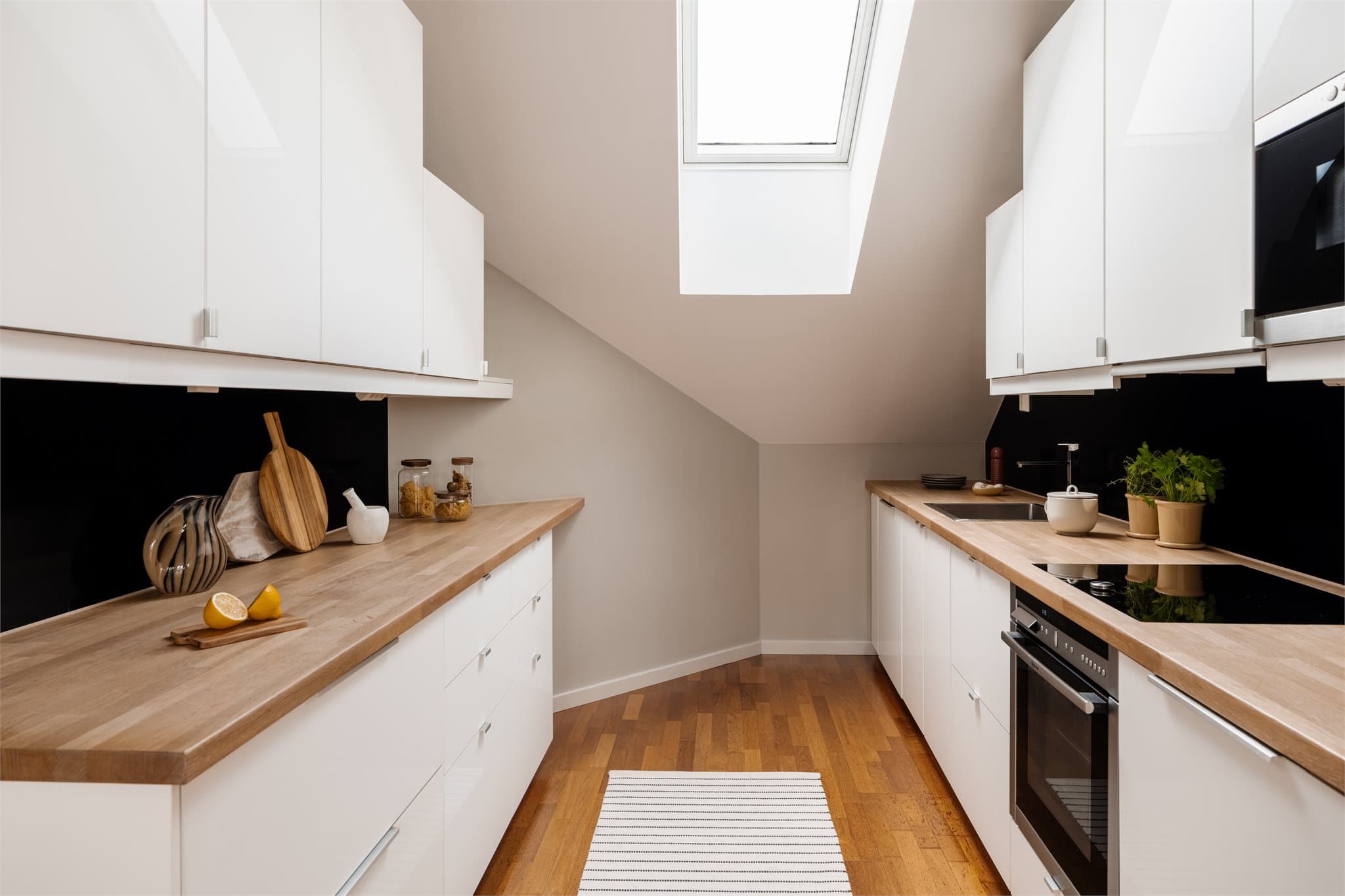 Lyst, moderne kjøkken med glatte fronter og benkeplater i eik.