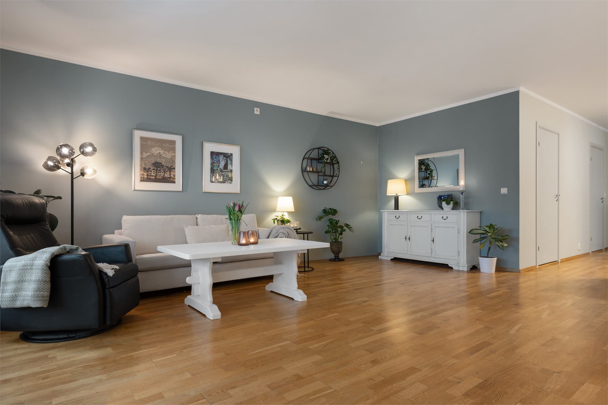 Fra spisestuen ledes romløsningen videre inn i en delvis lysmalt stue, hvor en lyseblå vegg tilfører rommet et friskt og rolig uttrykk.