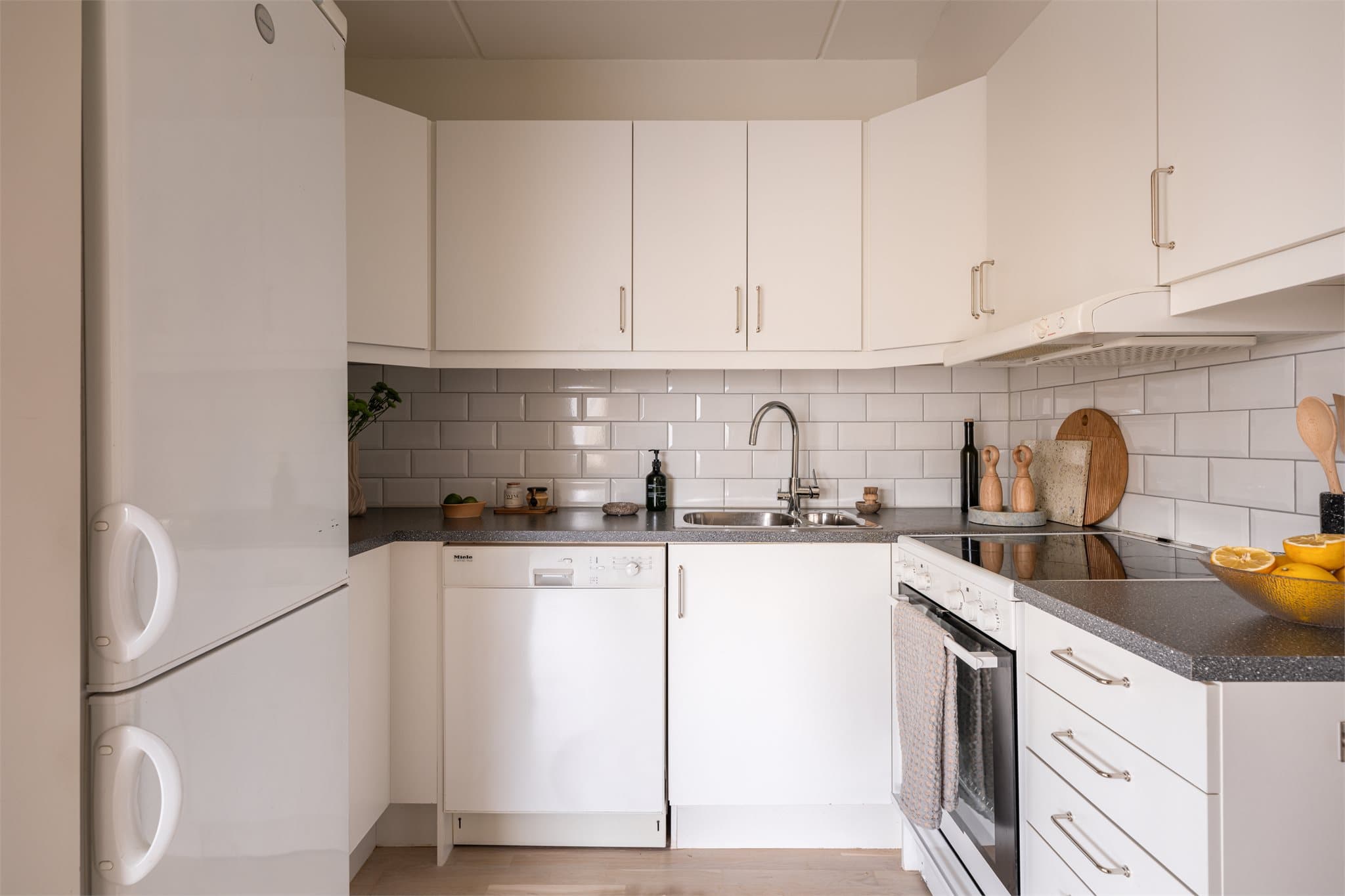 Kjøkkenet har fliser på veggen mellom over- og underskap.