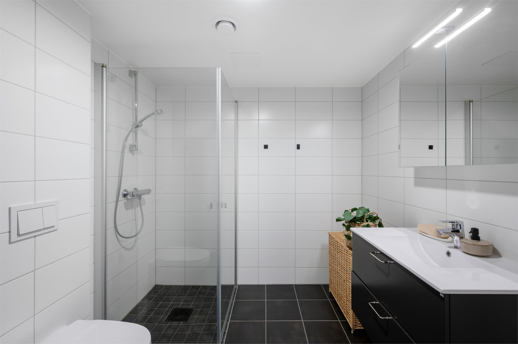 - Badet inneholder vegghengt toalett, heldekkende servant, speilskap med belysning, dusjdører i glass og opplegg for vaskemaskin -
