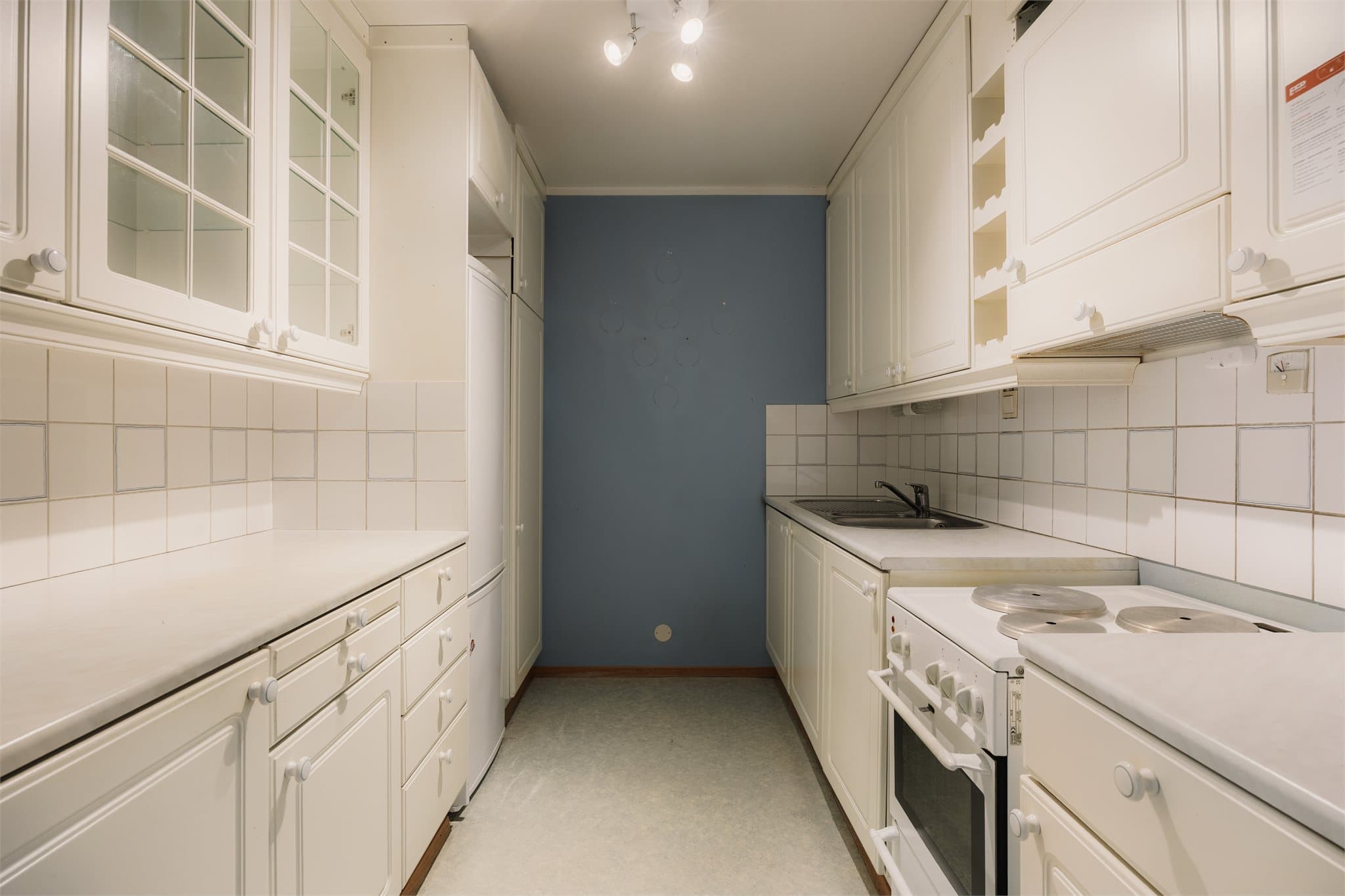 Kjøkkenet har en eldre innredning med glatte fronter og laminat benkeplate.