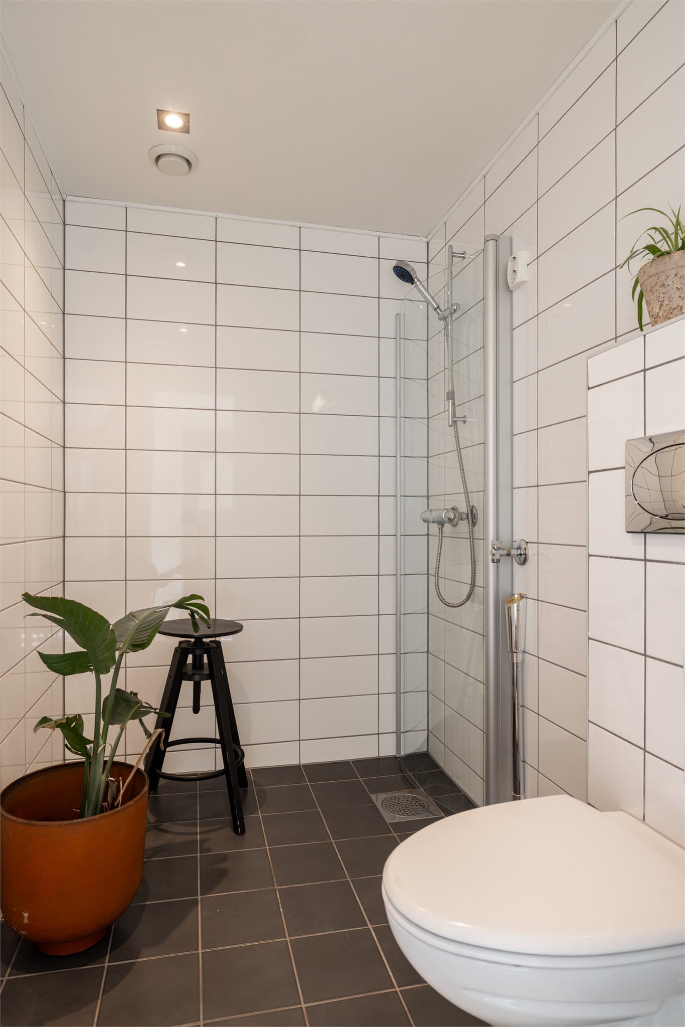 Et flislagt baderom med gulvvarme og downlights i taket.