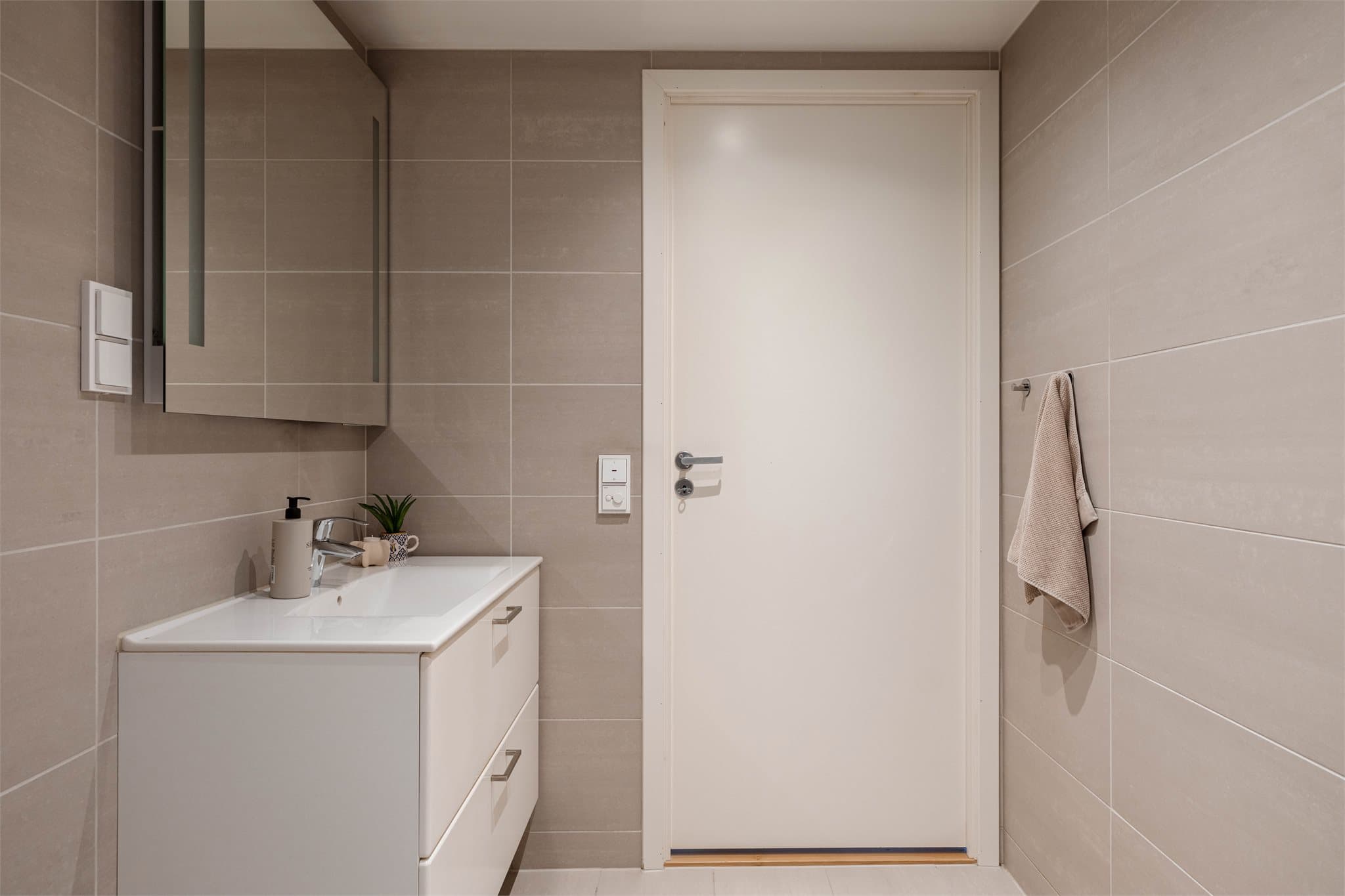 Badet er innredet med vegghengt toalett og servant. Fordelerskapet for rør-i-rør-systemet er plassert her.