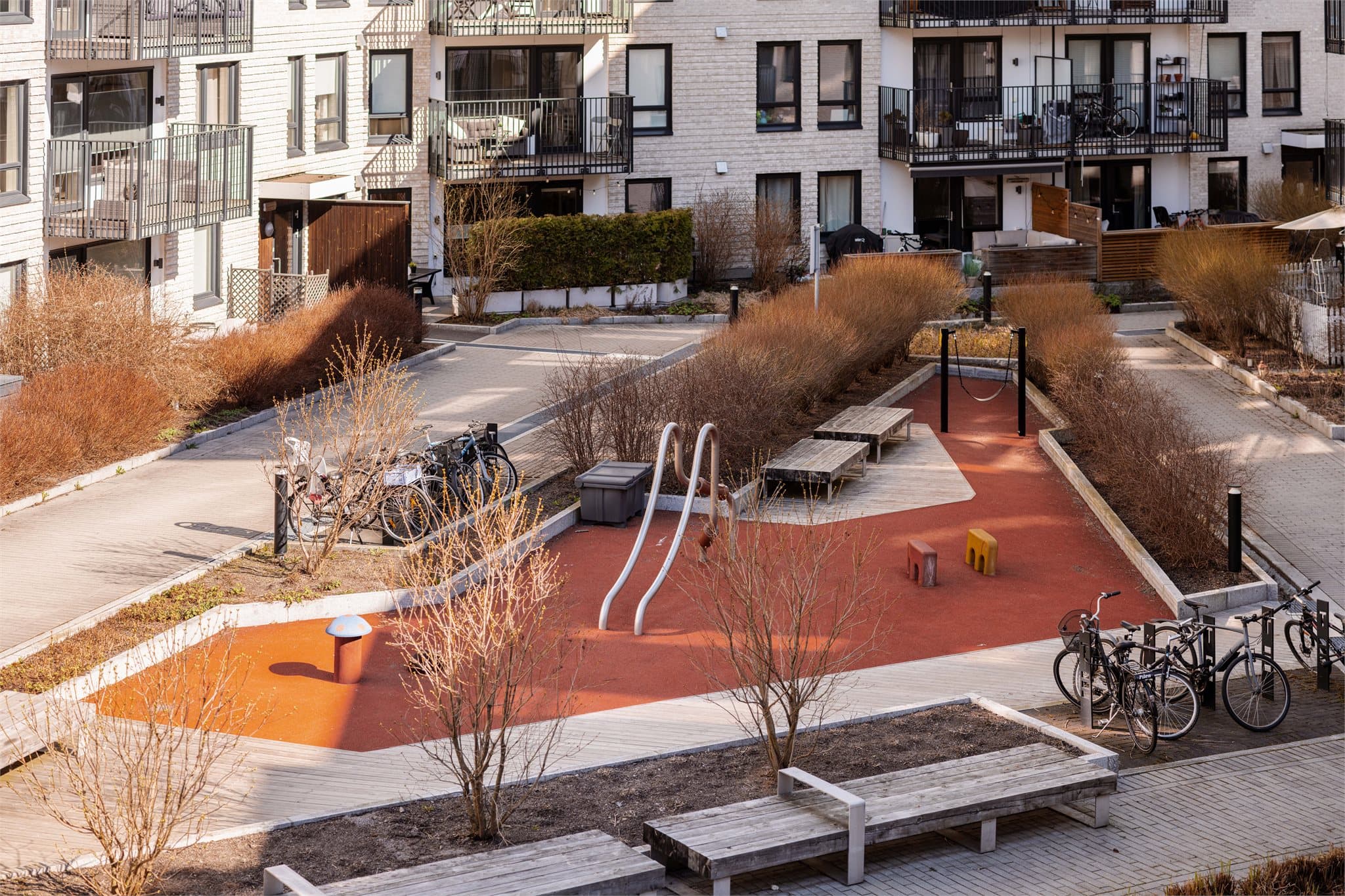 I gårdsrommet er det lekeapparater og sittebenker til glede for beboerne.