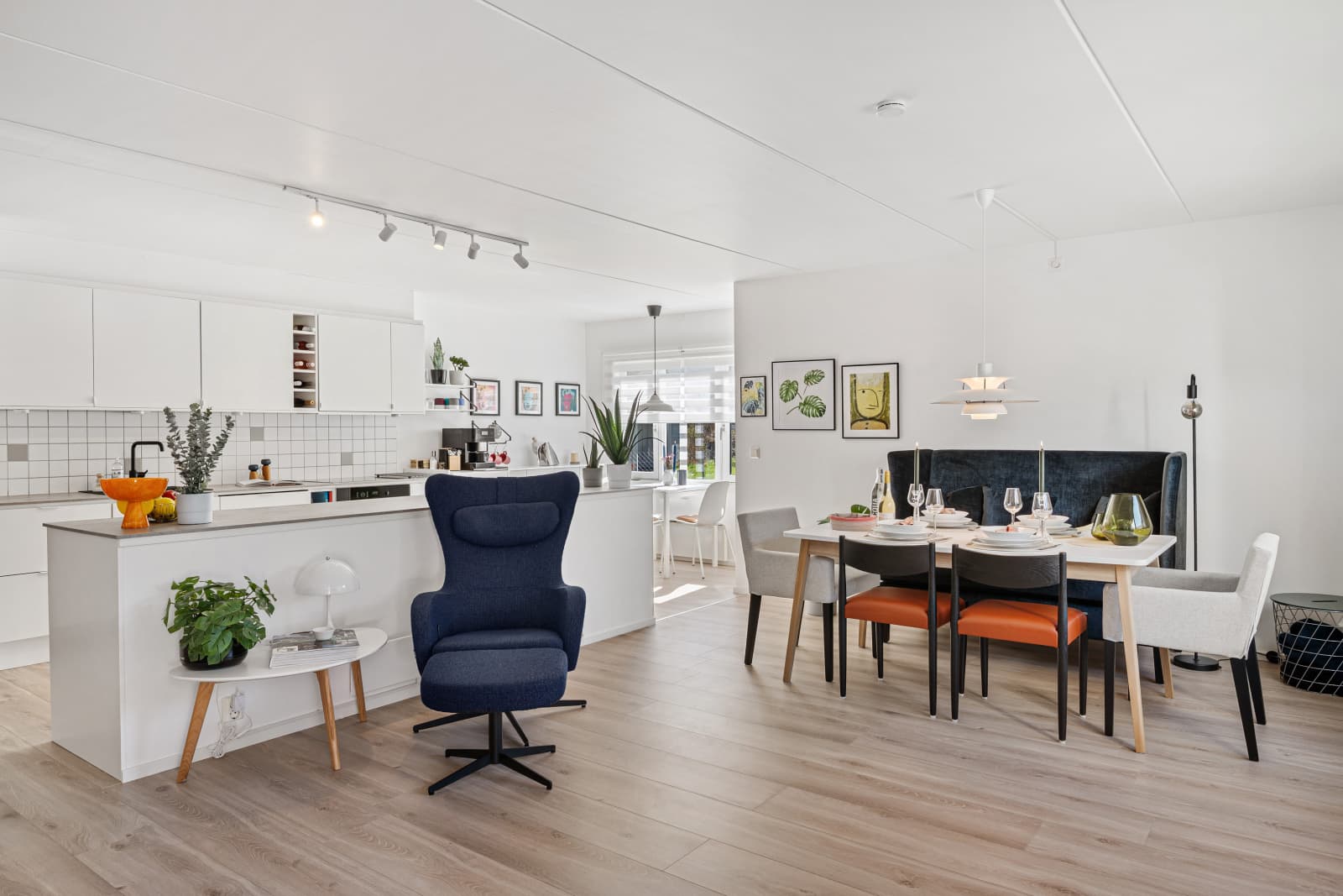 Spisestuen er plassert som en naturlig forlengelse av stuen, med god plass til et større spisebord – perfekt for hyggelige middager med familie og venner. I bakkant ligger det stilrene kjøkkenet, som både er funksjonelt og visuelt tiltalende.