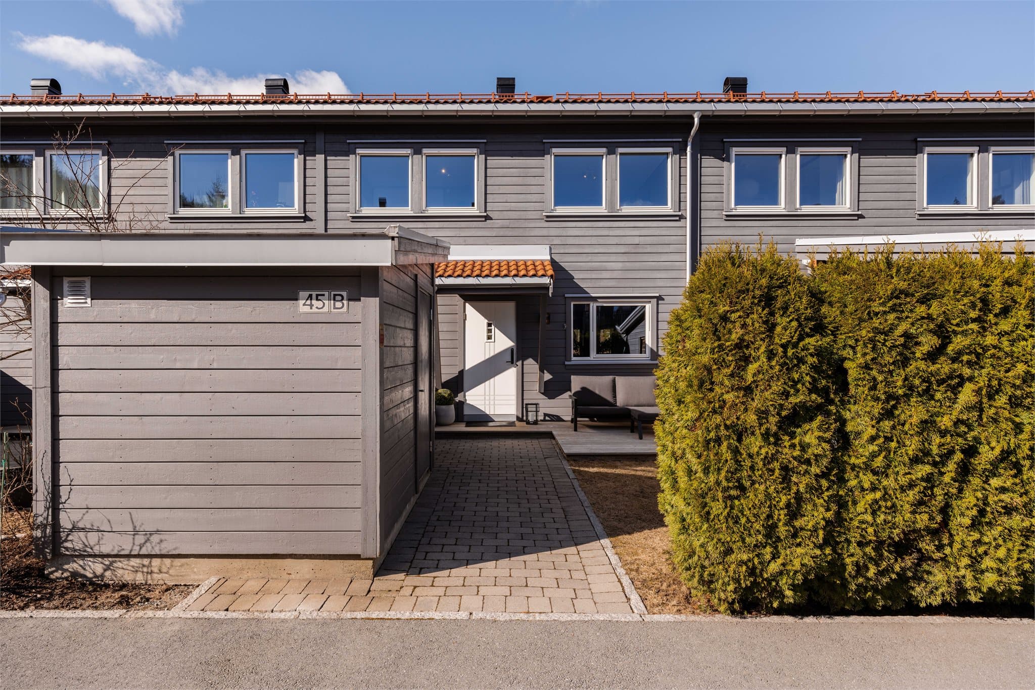 Rekkehuset har en pen og velholdt fasade med panelkledning og takstein fra byggeåret 2012. To uteboder med god lagringsplass.