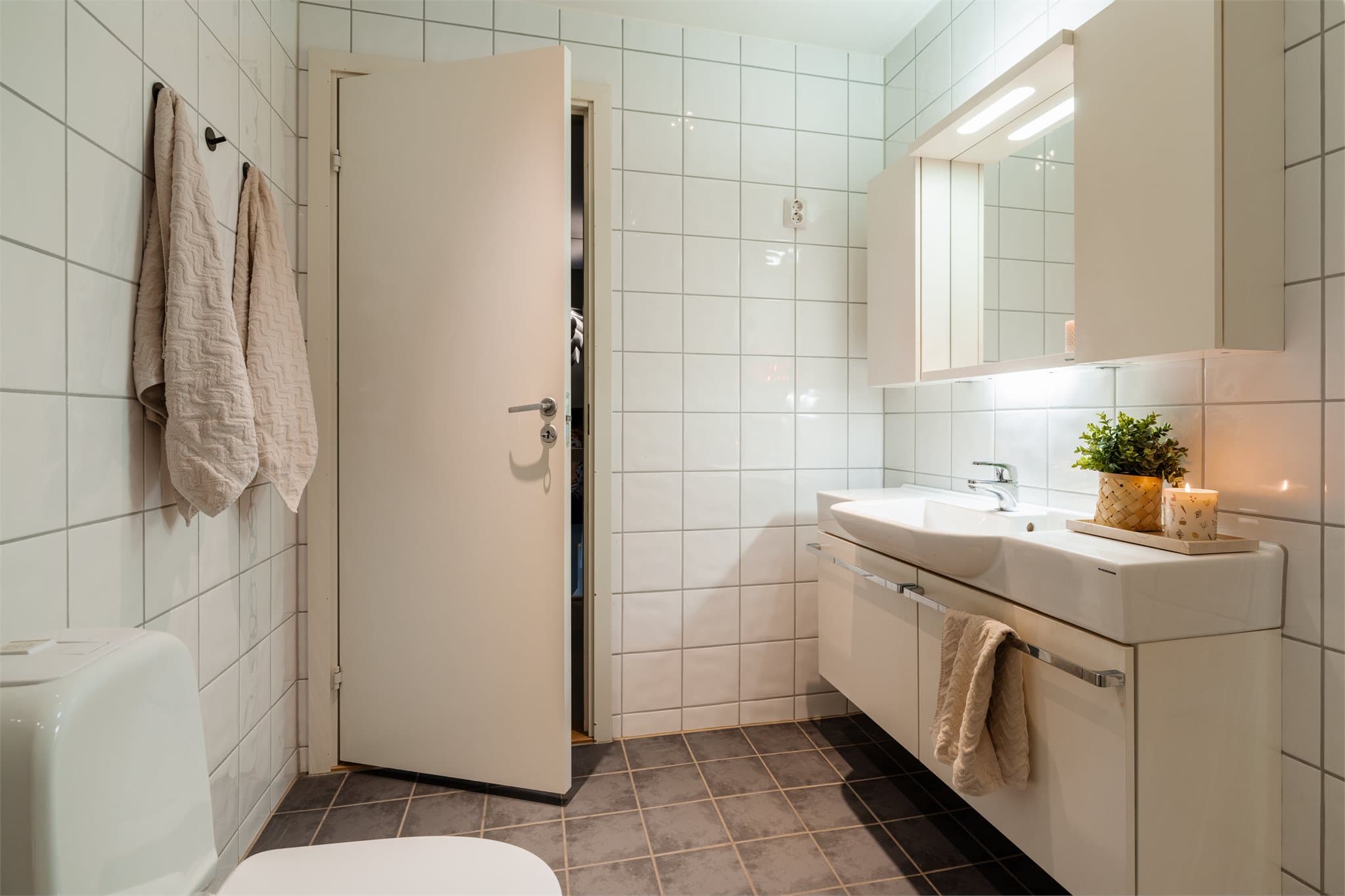 Dette er et funksjonelt bad med slett innredning, heldekkende servant og mekanisk avtrekk.