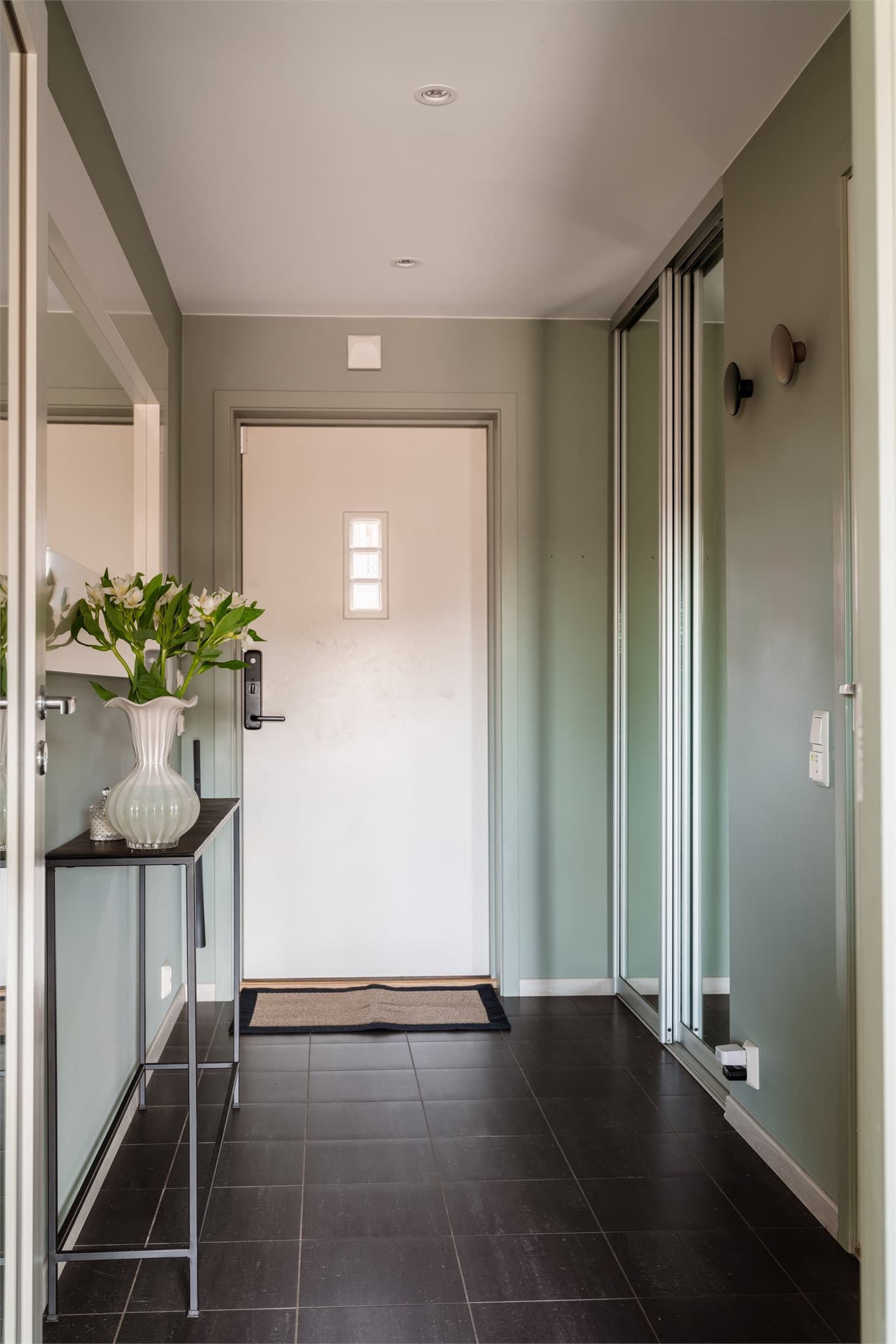 Her ønskes du inn i en innbydende entré med flislagt gulv og varmekabler. En praktisk skyvedørsgarderobe skjuler sko og yttertøy.