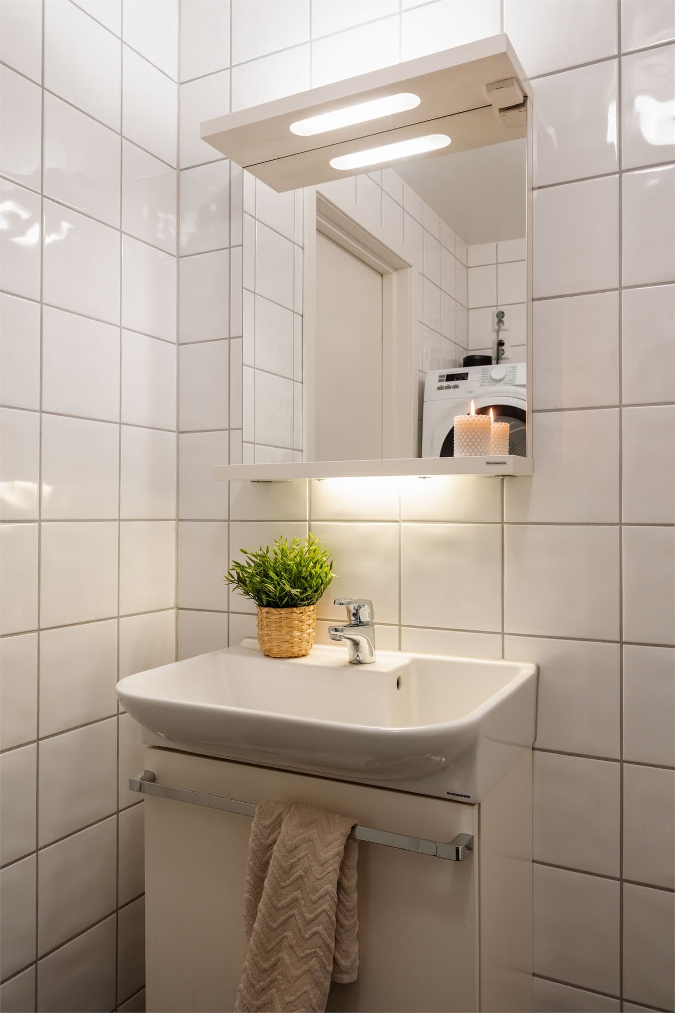 Badet er utstyrt med toalett, dusj, slett innredning, servant og speil med belysning.