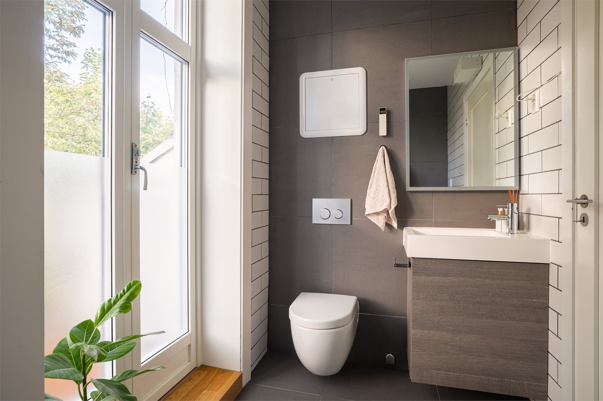 Delikat bad med grå og hvite fliser og varmekabler på gulv.