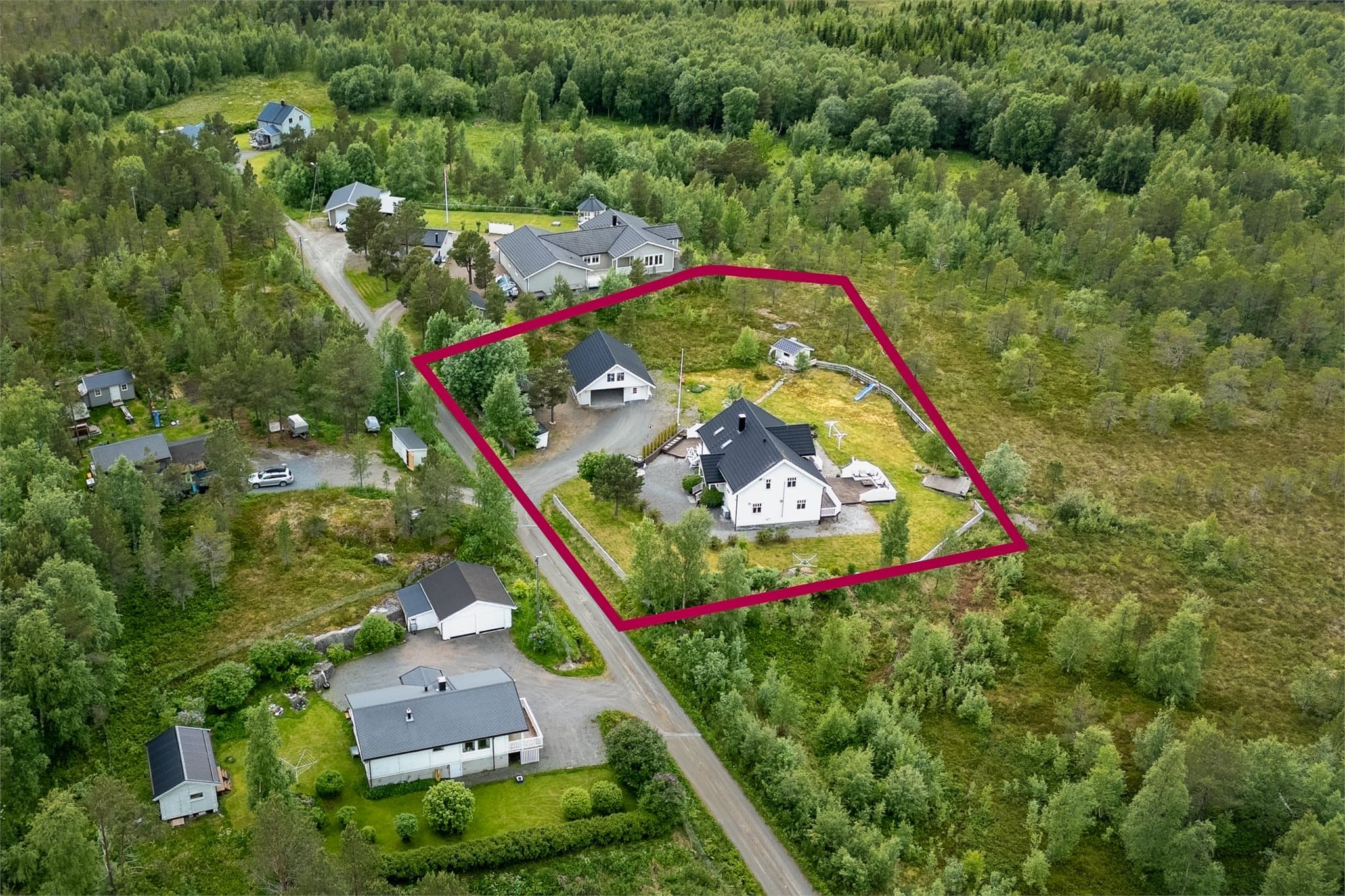 Stor tomt som er opparbeidet med gruset gårdsplass og flere uteplasser. (Skissert tomtegrenser)