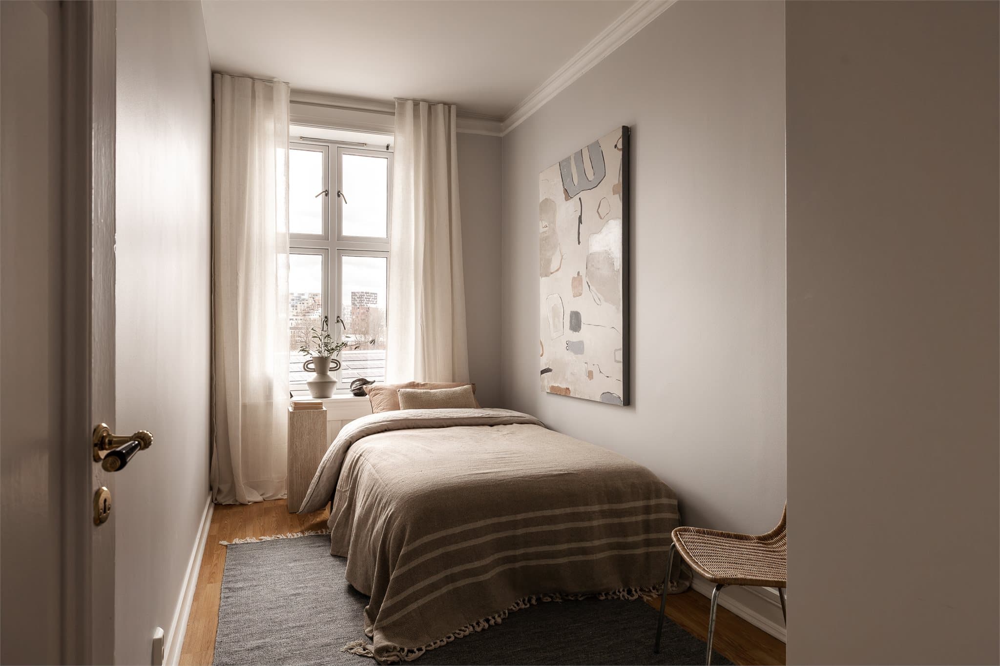 Vinduet slipper inn fint dagslys og gir rommet en luftig følelse, mens den rolige fargepaletten skaper en behagelig atmosfære.