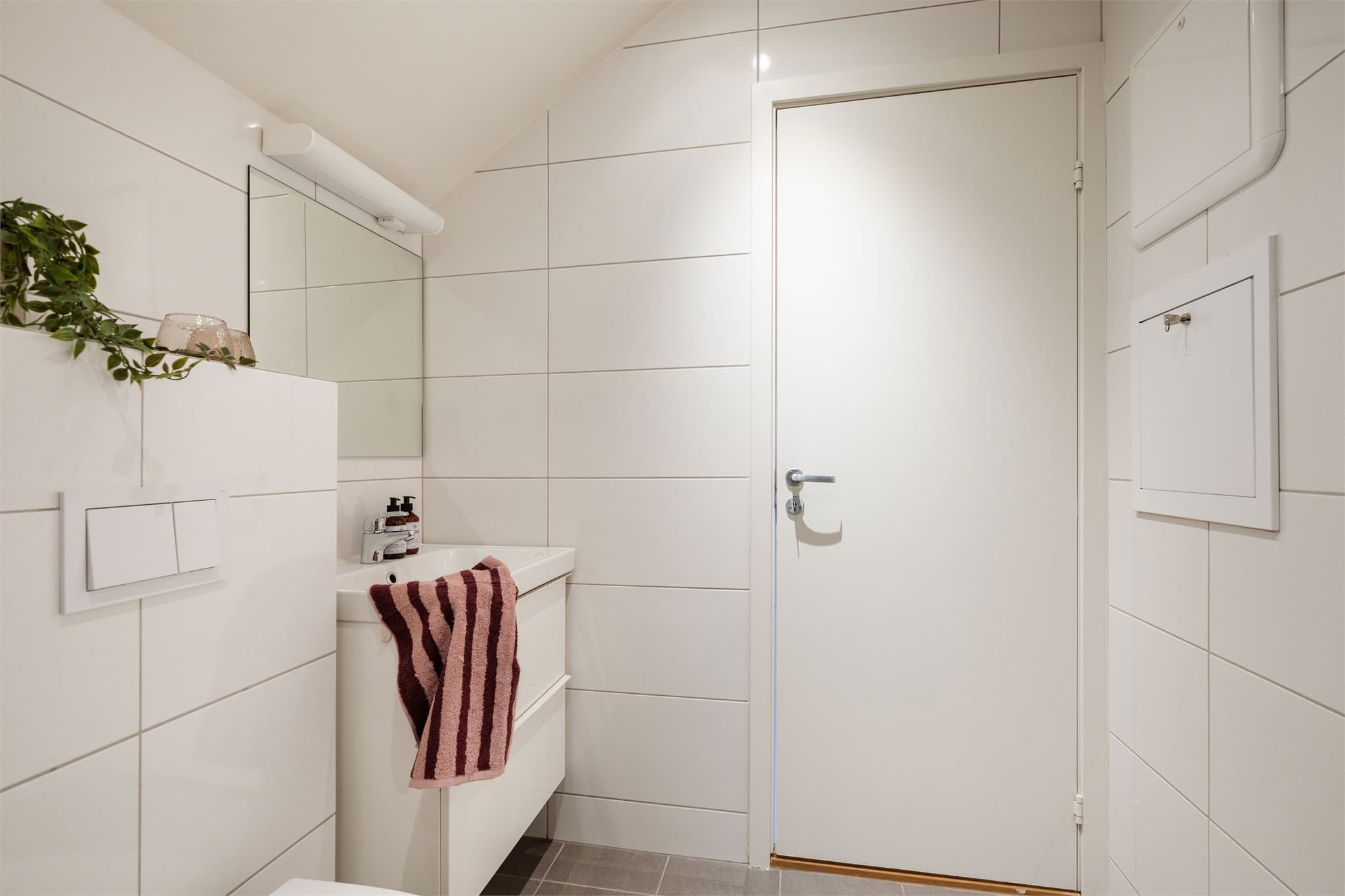 Badet er utstyrt med vegghengt toalett med innebygget sisterne og en servantinnredning med skapplass.