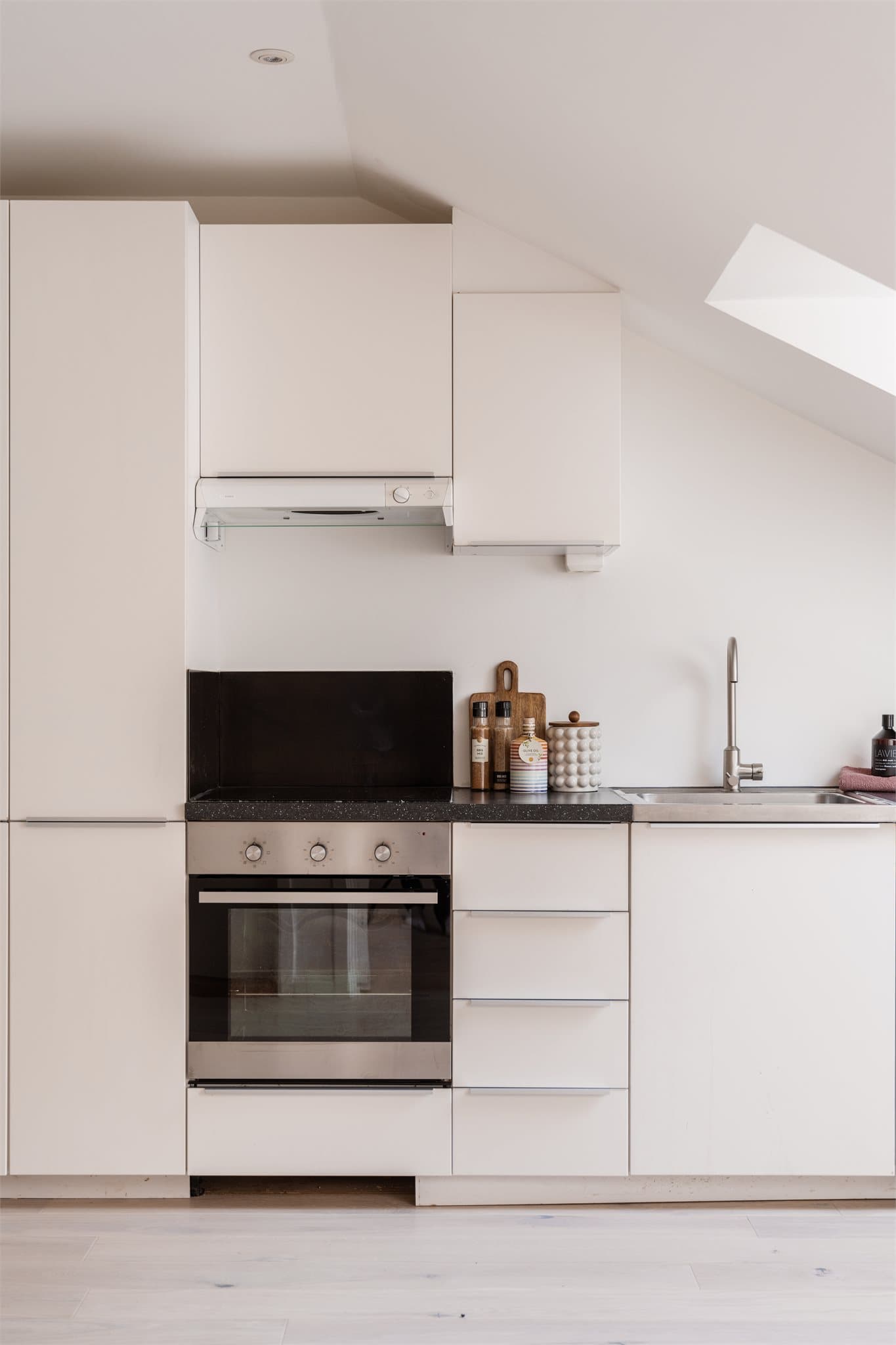 Kjøkkenet fra 2014 er pent integrert i oppholdsrommet og har et tidløst uttrykk med glatte fronter og laminat benkeplate.