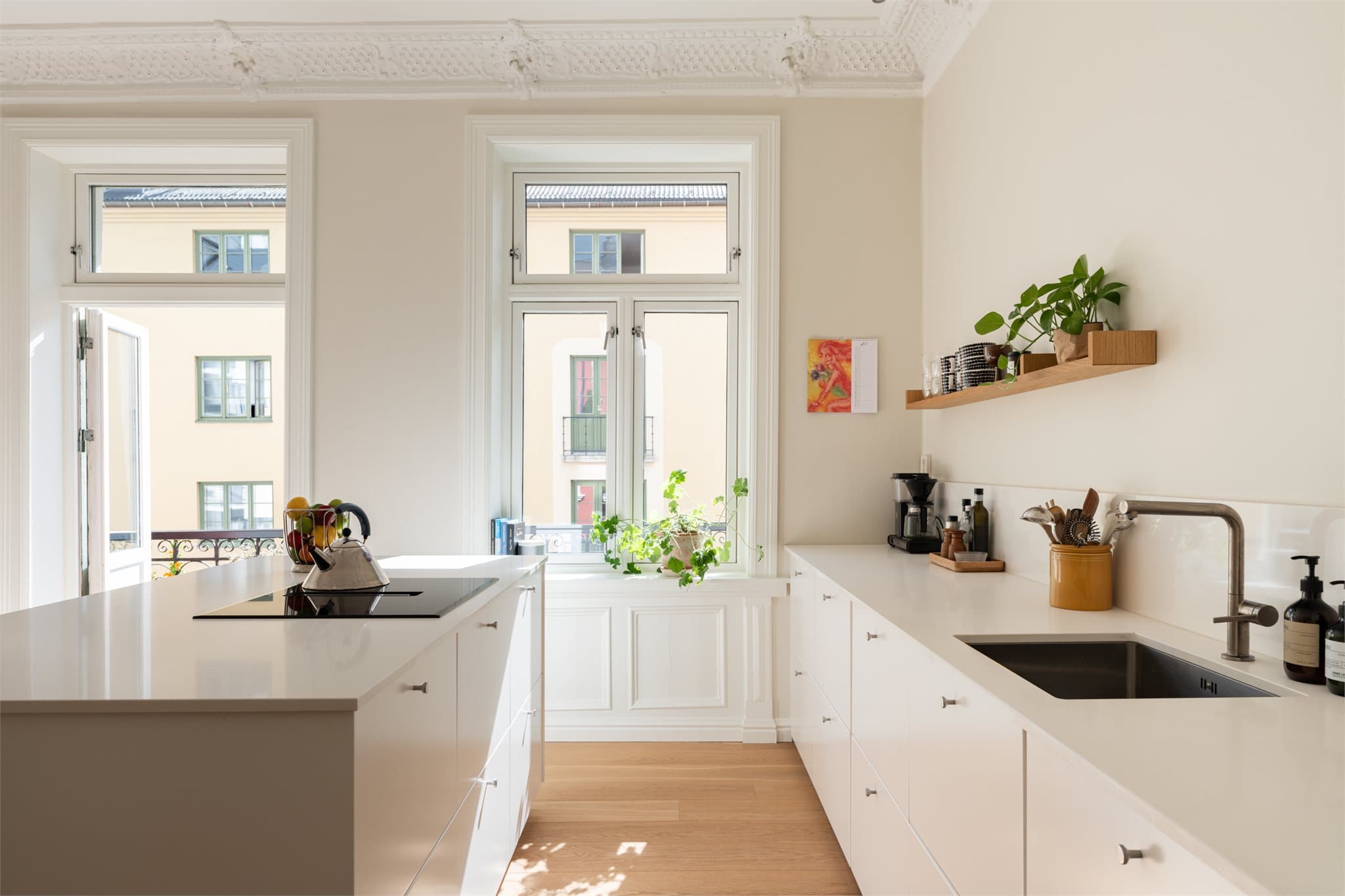 Lyse, glatte fronter kombineres med benkeplate i kompositt i matchende tone og integrerte hvitevarer.