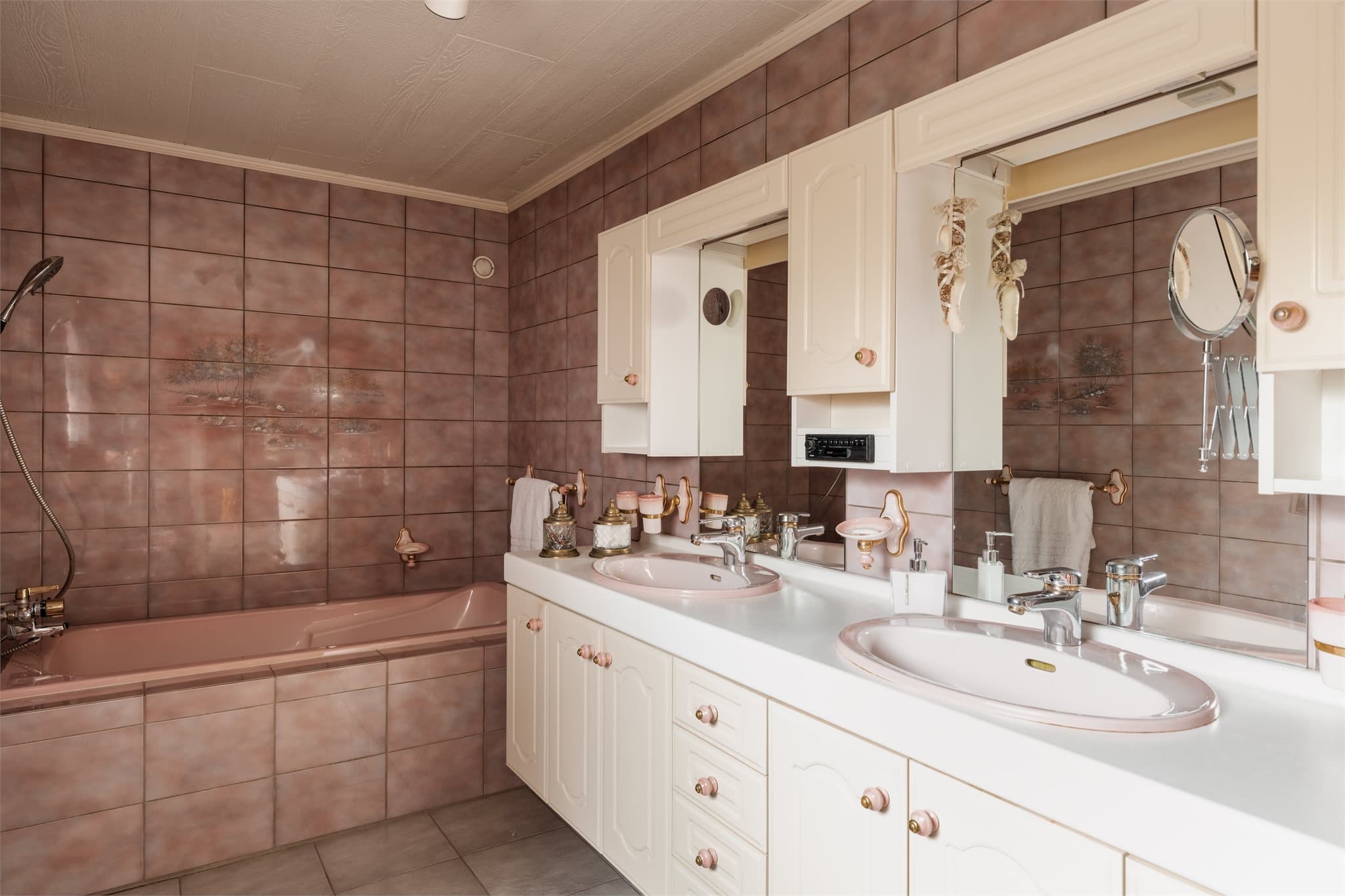 Rommet har flislagt gulv med gulvvarme og en praktisk innredning med dobbel servant.