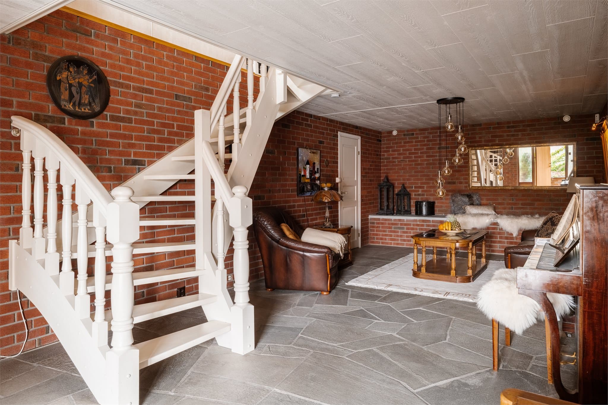 Inngangspartiet går over i en romslig kjellerstue med karakteristiske vegger i teglstein.