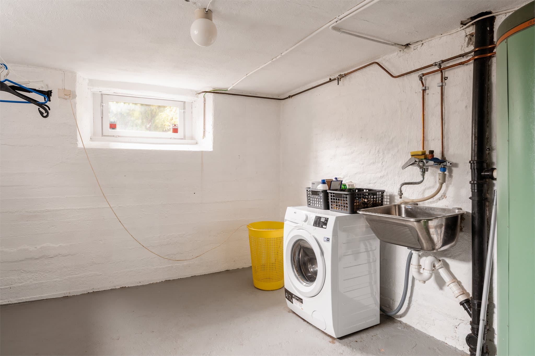 Et separat og romslig vaskerom med opplegg for vaskemaskin og utslagsvask.