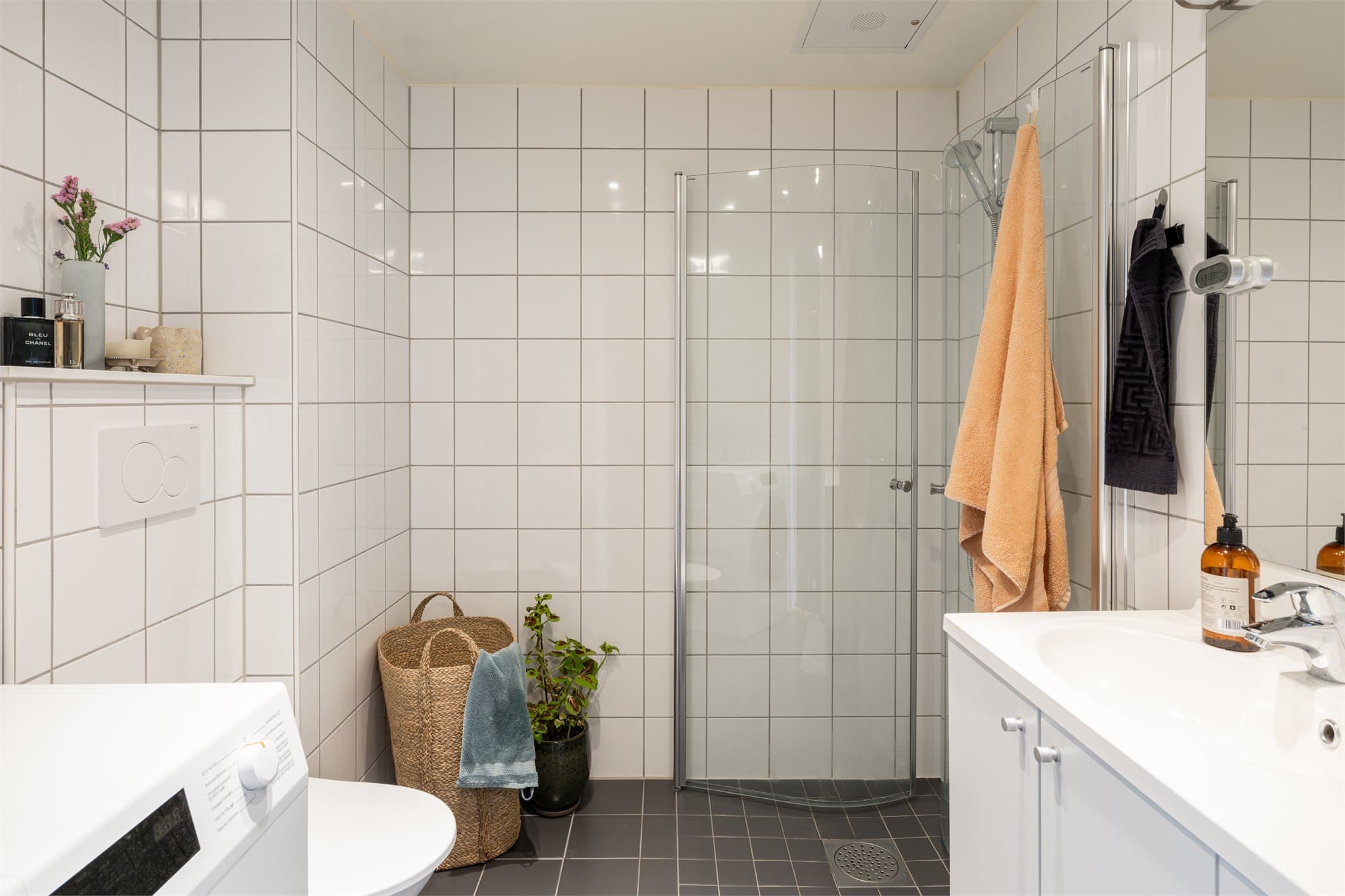 Det lyse, flislagte badet har elektriske varmekabler i gulvet. På venstre side er det opplegg for vaskemaskin.