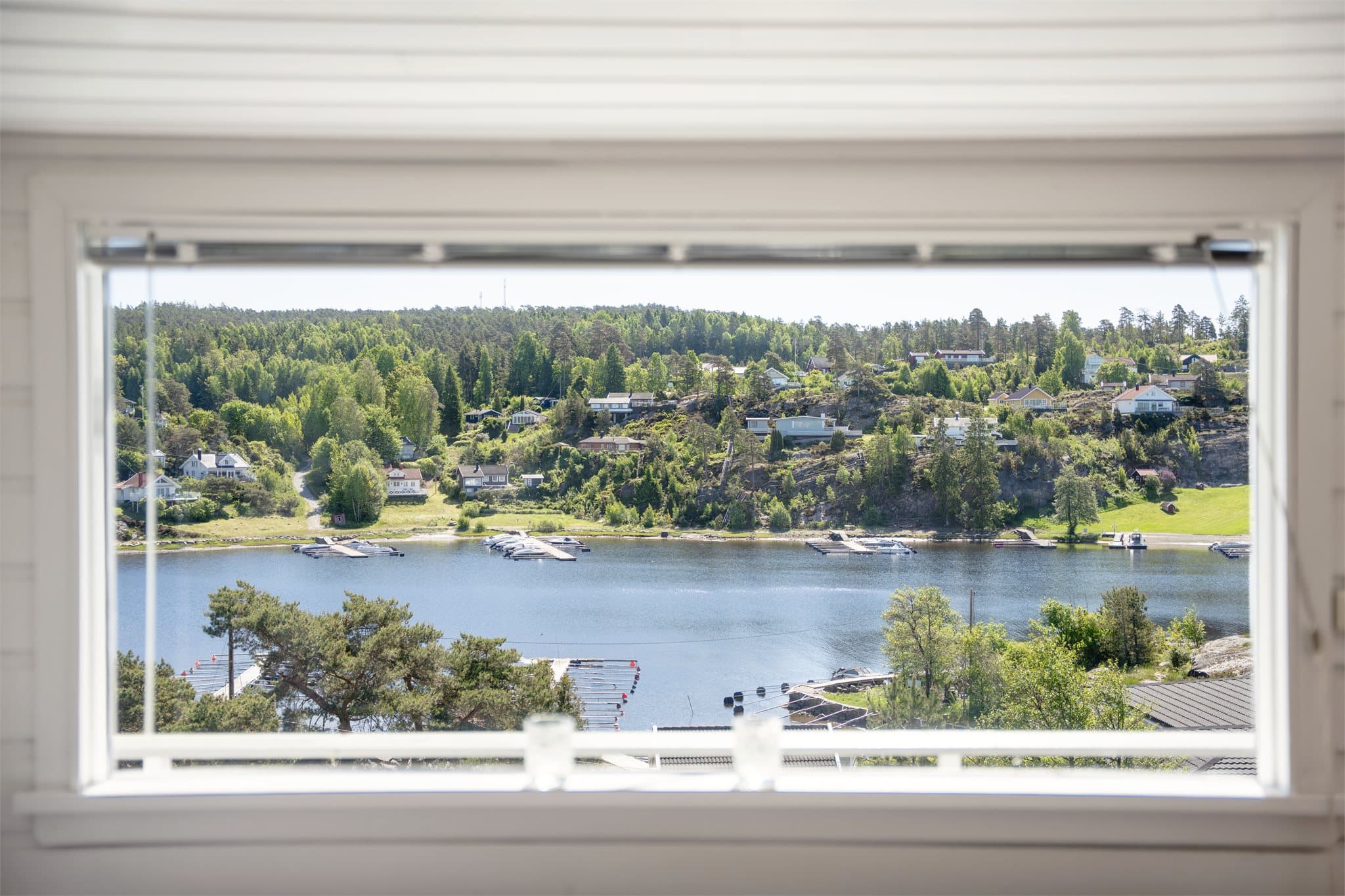Utsikt fra vinduet mot nærområdet og sjøen.