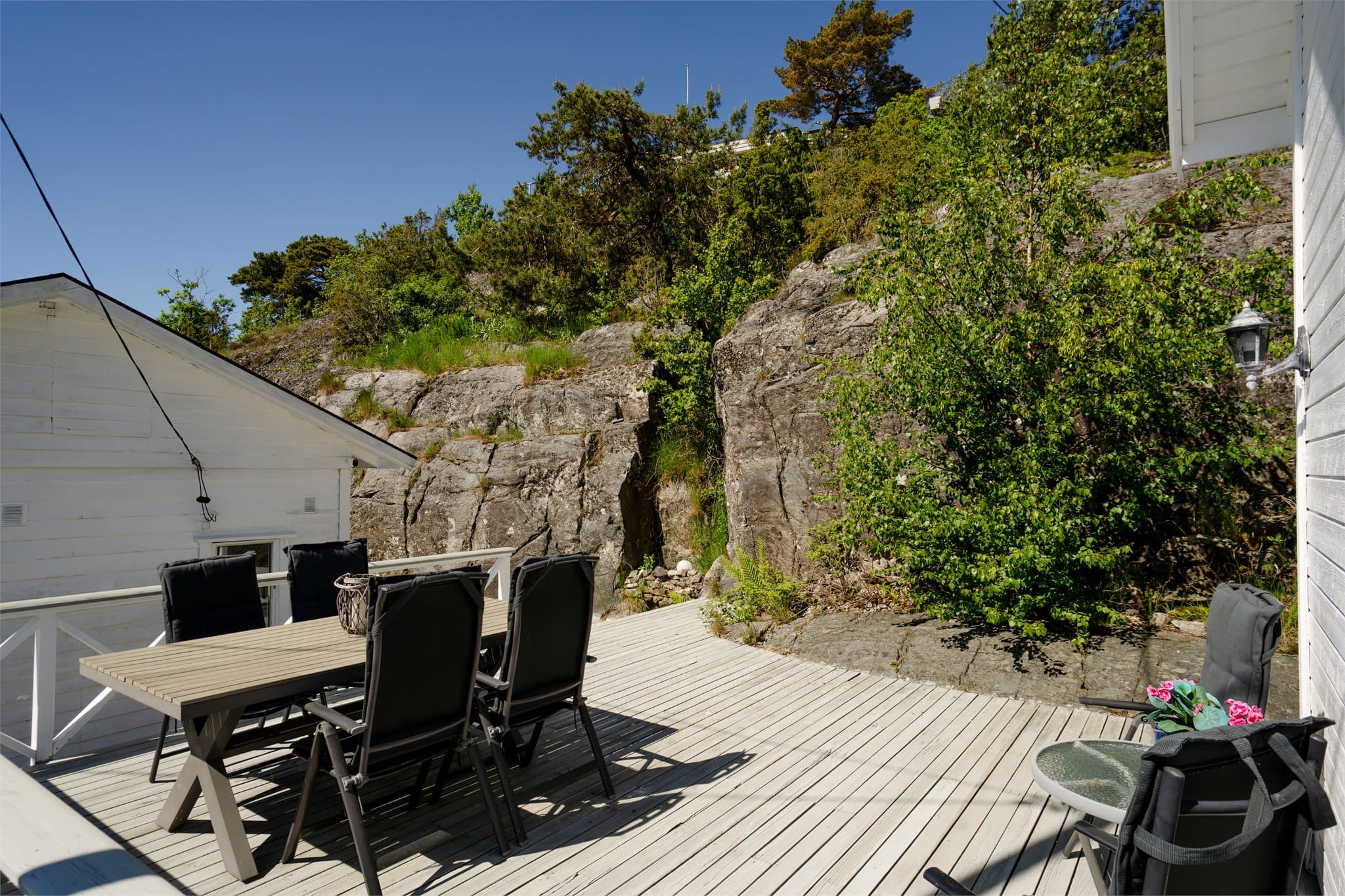 Eiendommen ligger lunt til, med fjellknauser som en naturlig del av omgivelsene.