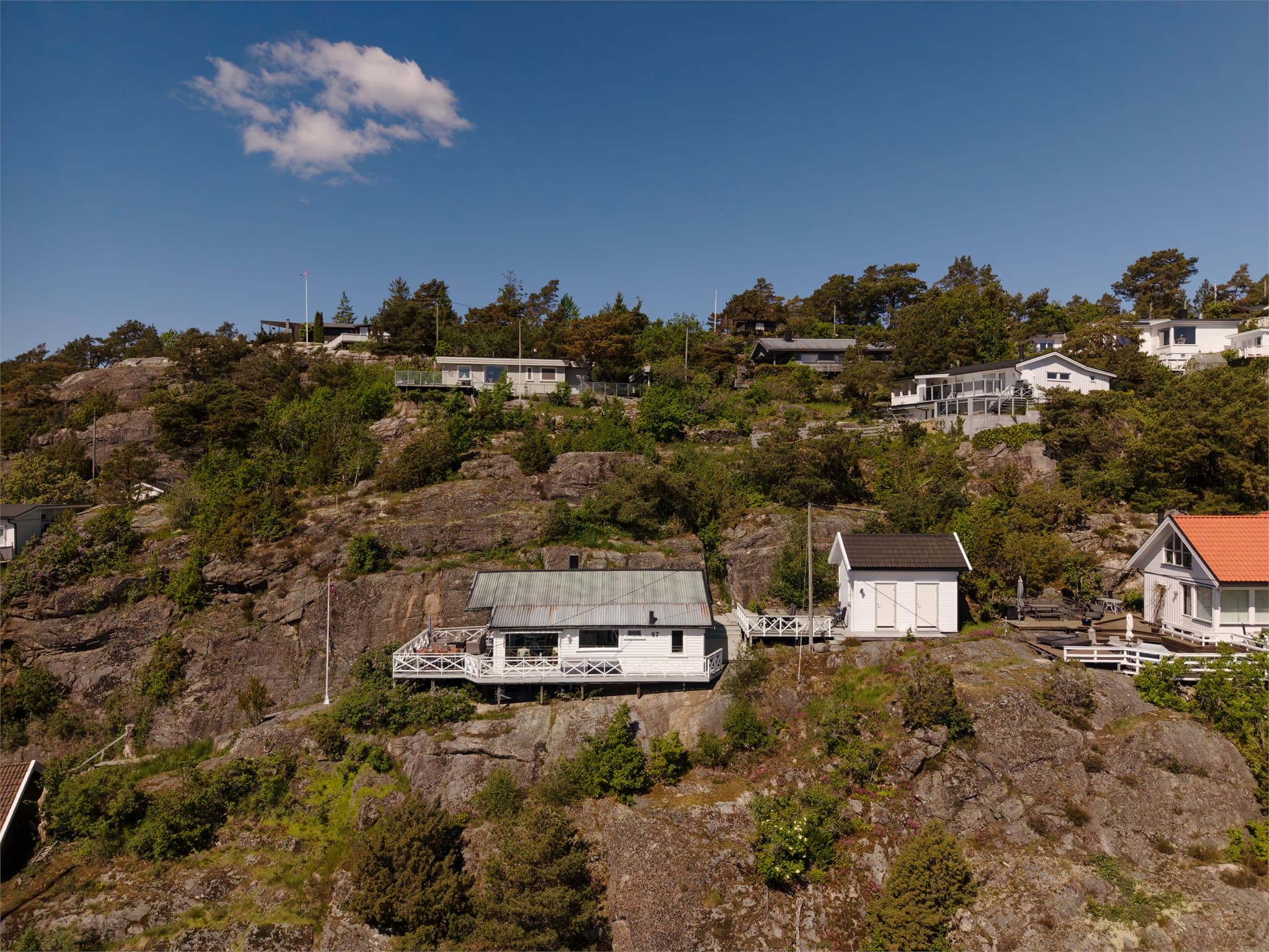 Oversikt over hytta og annekset, plassert på en fjellgrunn.