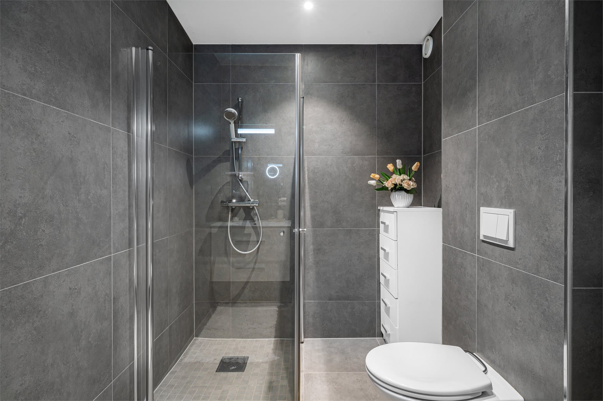 - Badet er innredet med heldekkende servant, vegghengt toalett og dusjdører i glass -