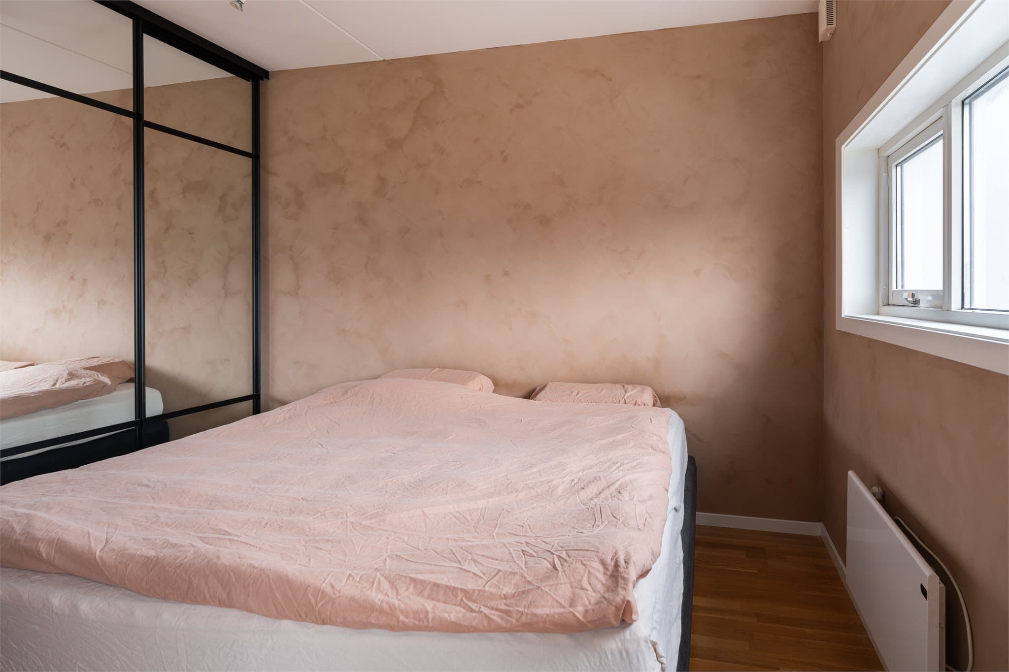 Leiligheten tilbyr ett soverom av god størrelse. Det er god plass til dobbeltseng og nattbord på hver side.