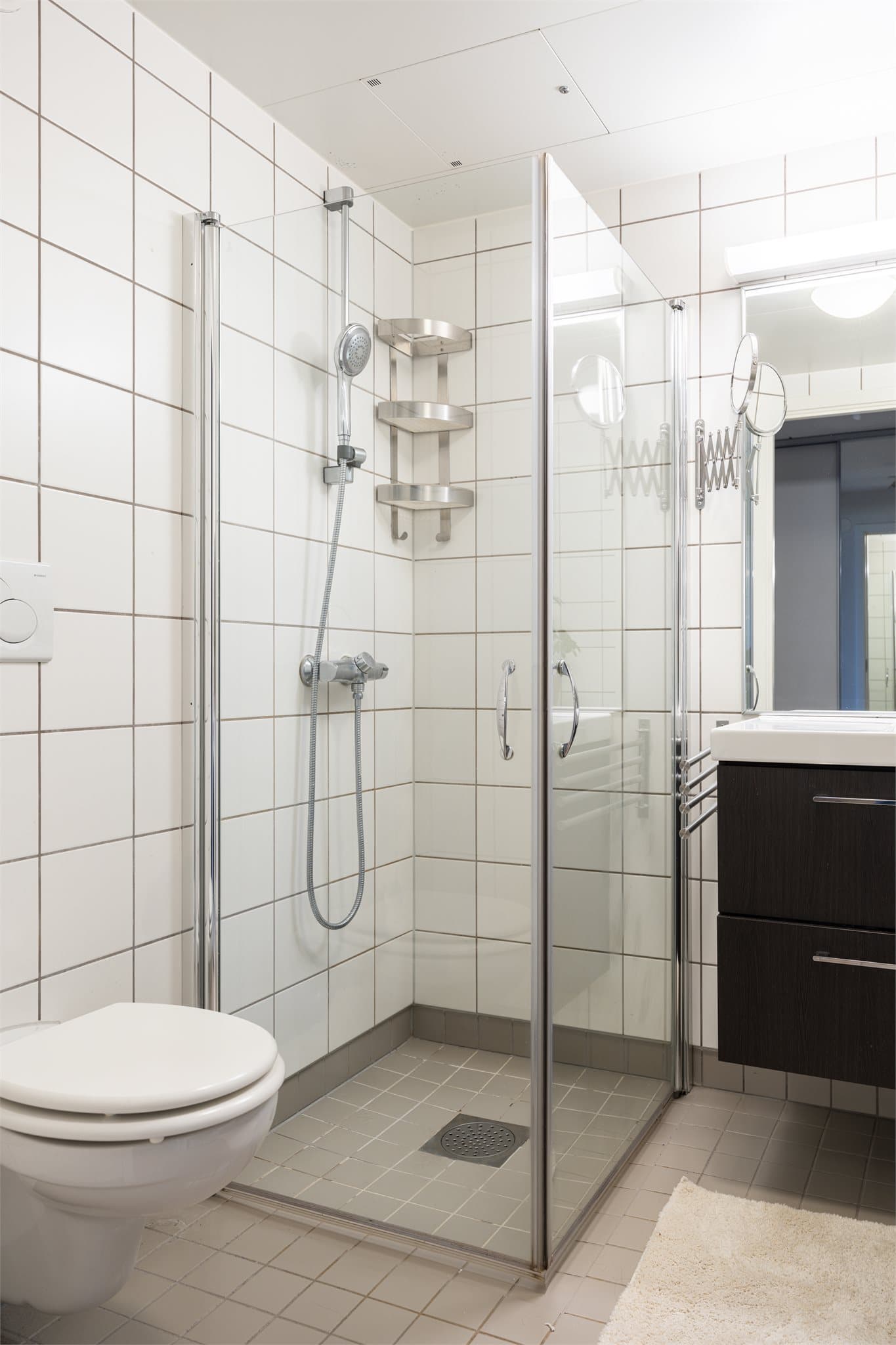 Videre finner du et dusjhørne med svingdører, vegghengt toalett og opplegg for vaskemaskin.