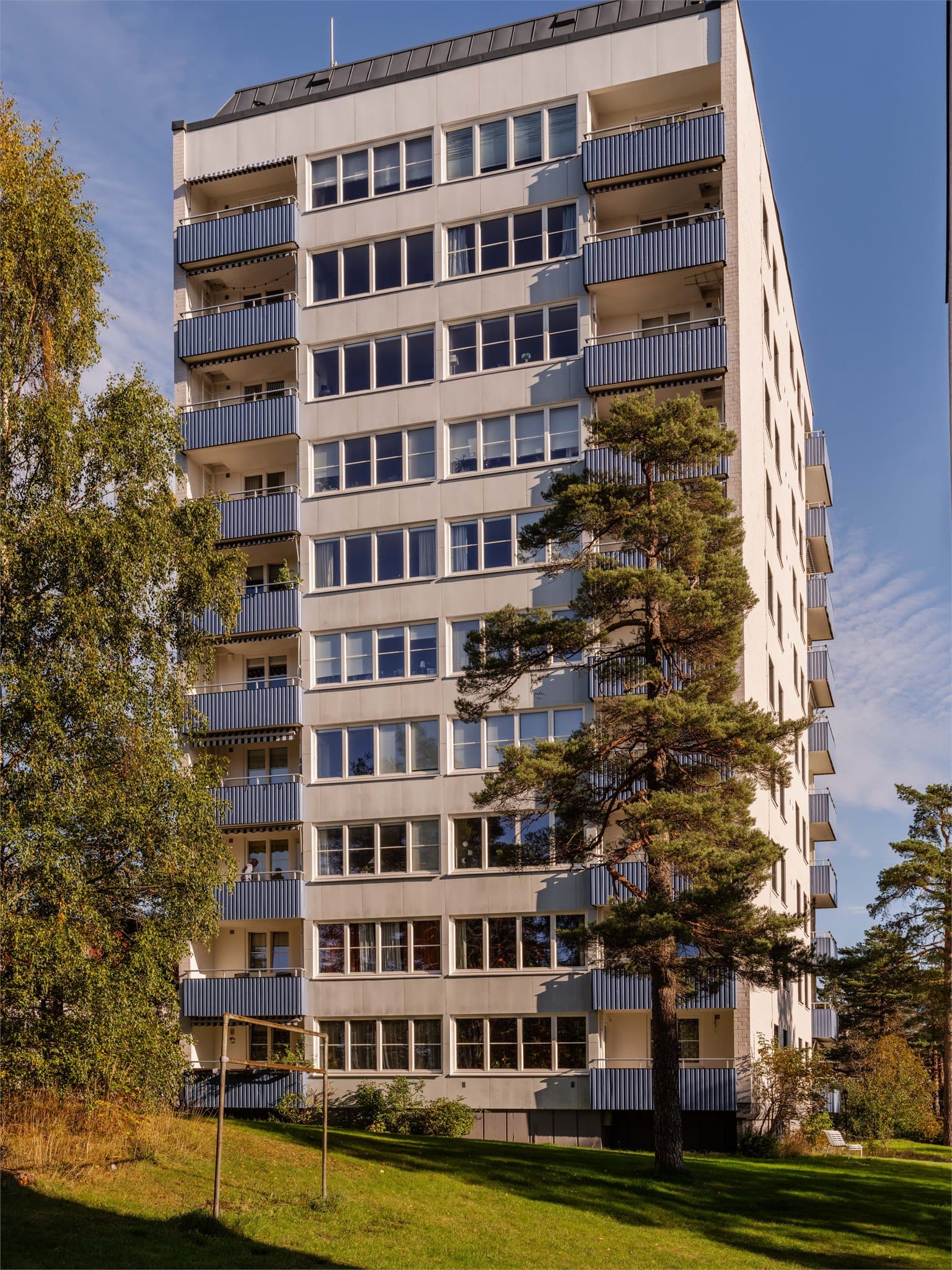 Boligblokken ligger skjermet til i grønne omgivelser, med heis i bygget.