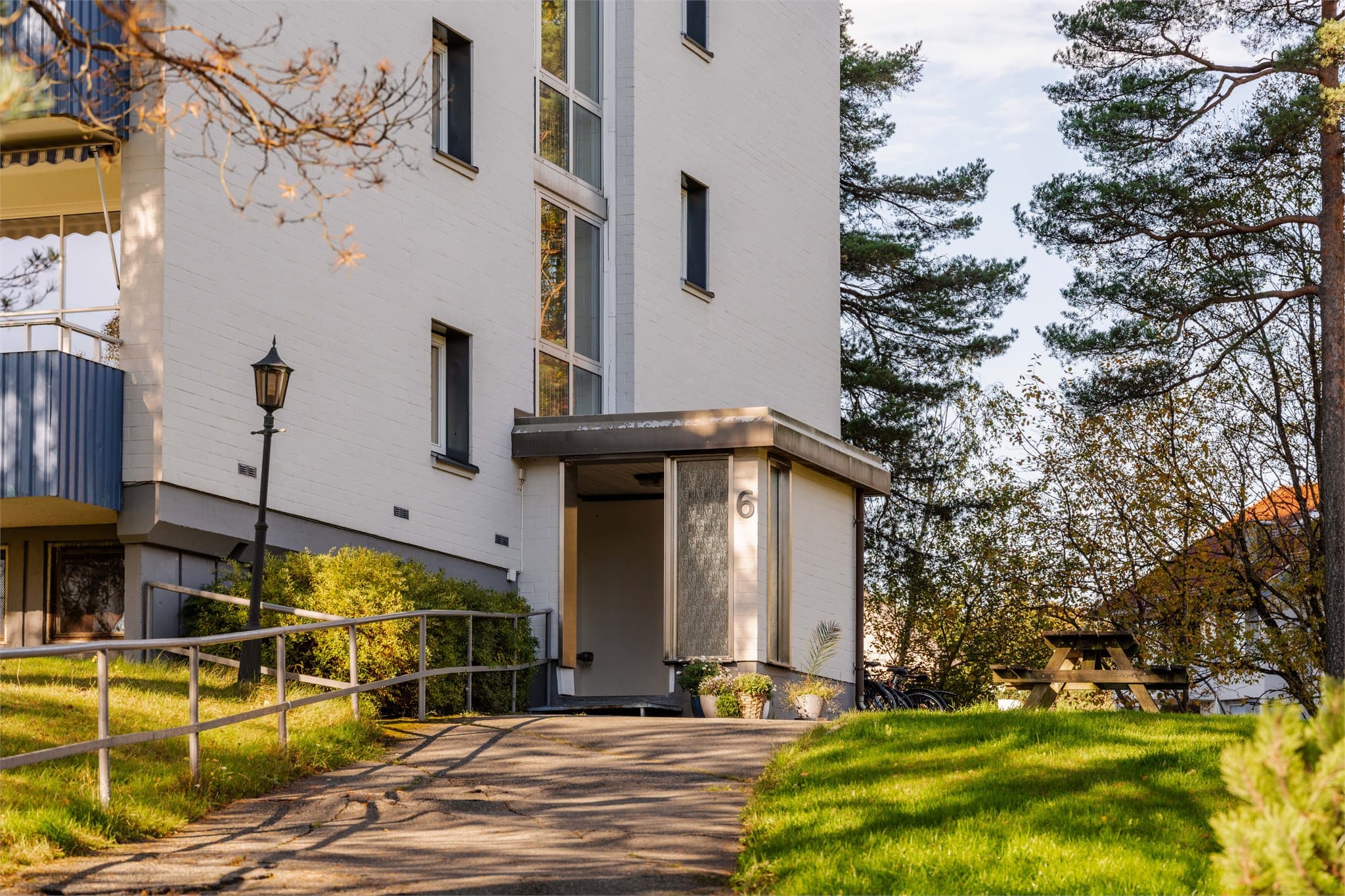 Inngangsparti med overbygd vindfang og sittebenk på fellesarealet.