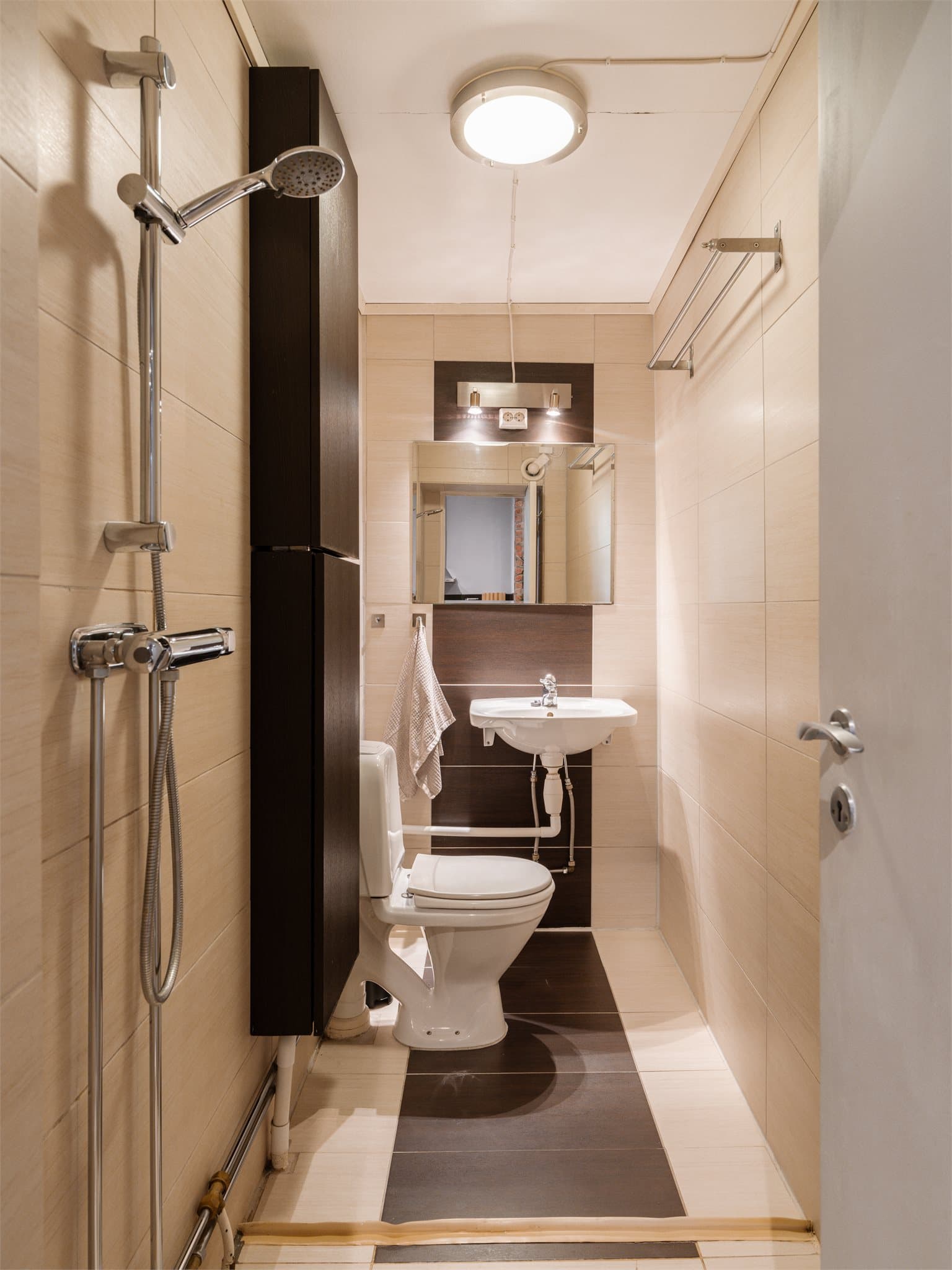 Badet er helfliset og innredet med toalett, servant og en egen dusjsone.