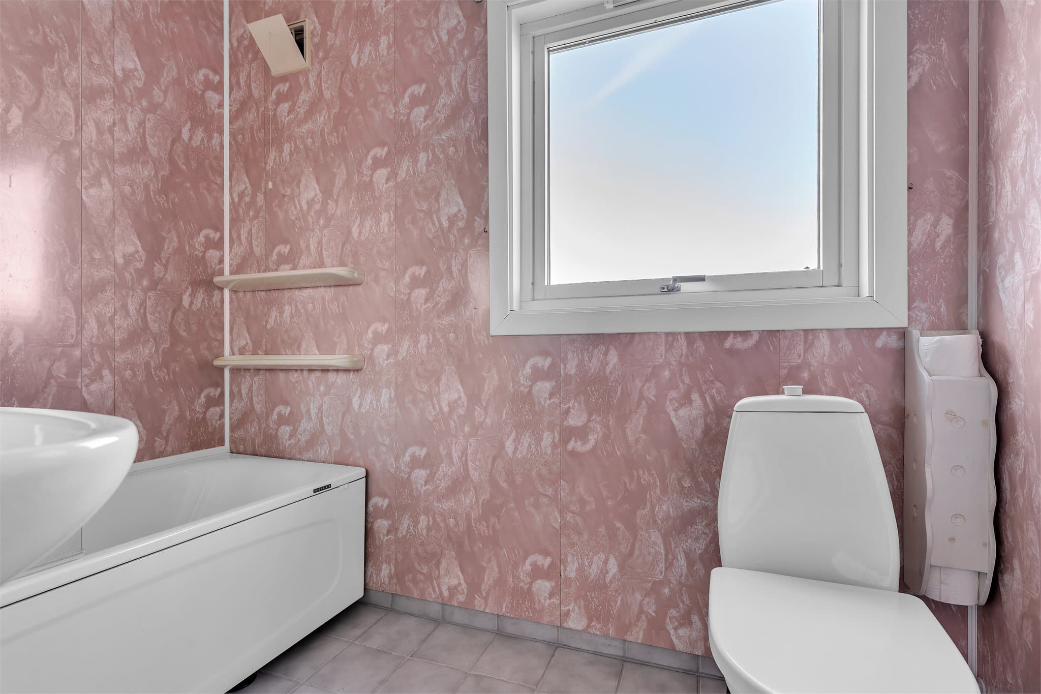 Badet i 1. etasje har flislagt gulv med gulvvarme, badekar og toalett.