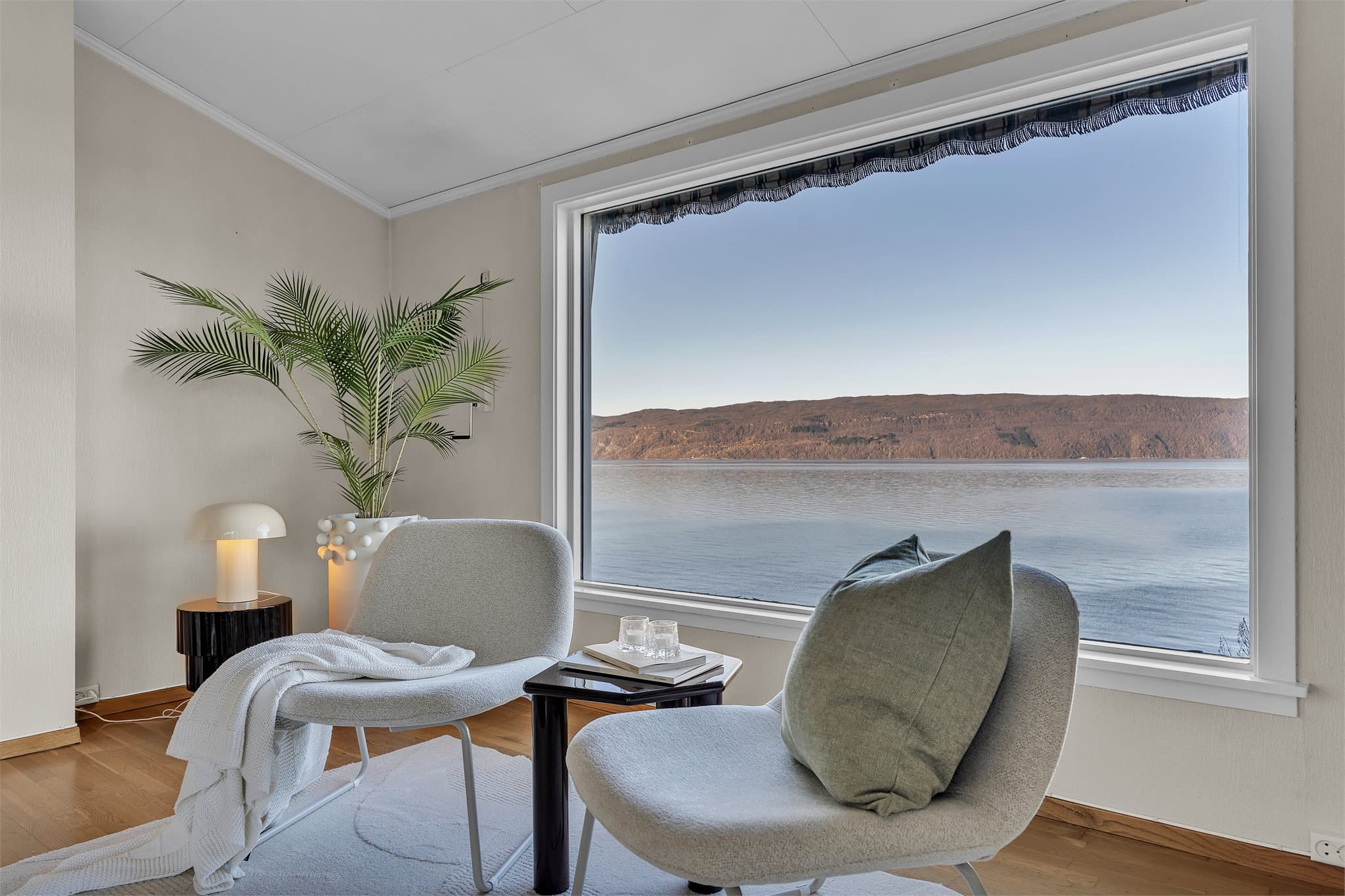 Stuen i hovedetasjen har ekstra takhøyde og store vindusflater som rammer inn fjordlandskapet.