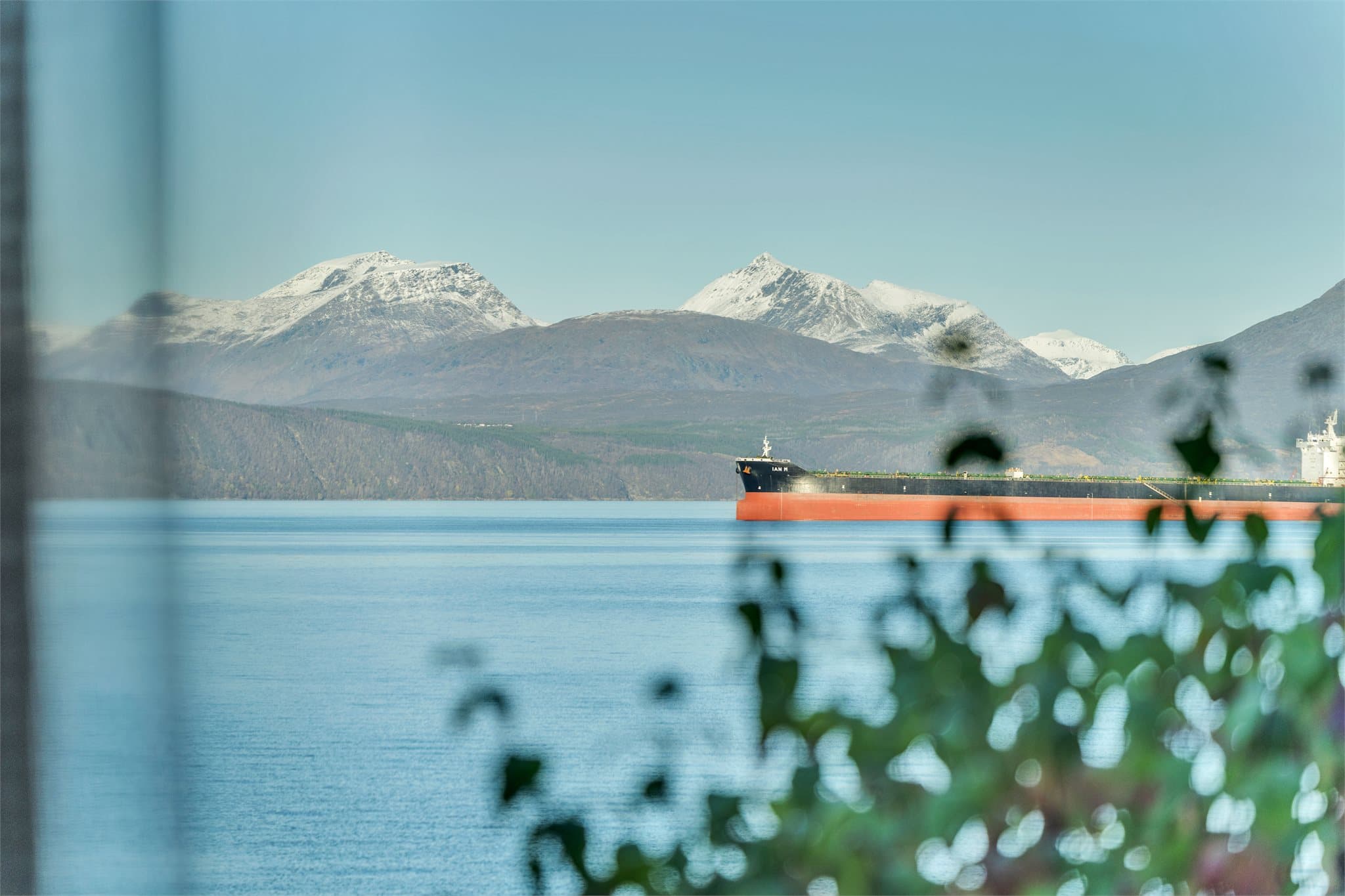 Vinterkledde fjelltopper speiler seg i det klare fjordvannet.