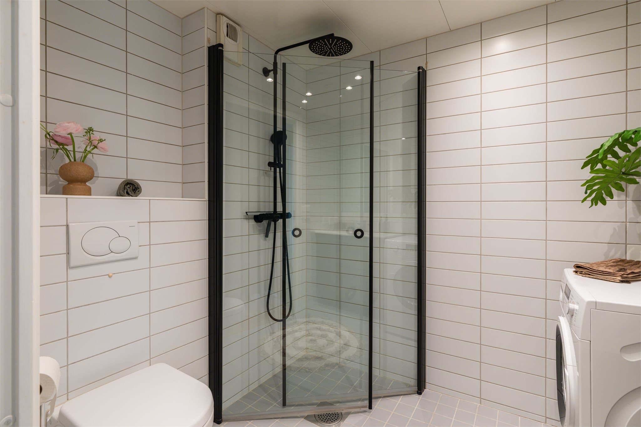 Dusjhjørne med innfellbare glassdører og vegghengt toalett.