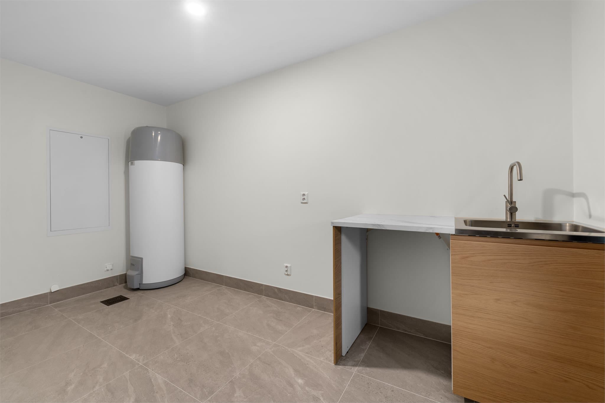 Stort separat vaskerom med vaskeromsinnredning i samme stil som kjøkkenet. Fliser og varme i gulv.