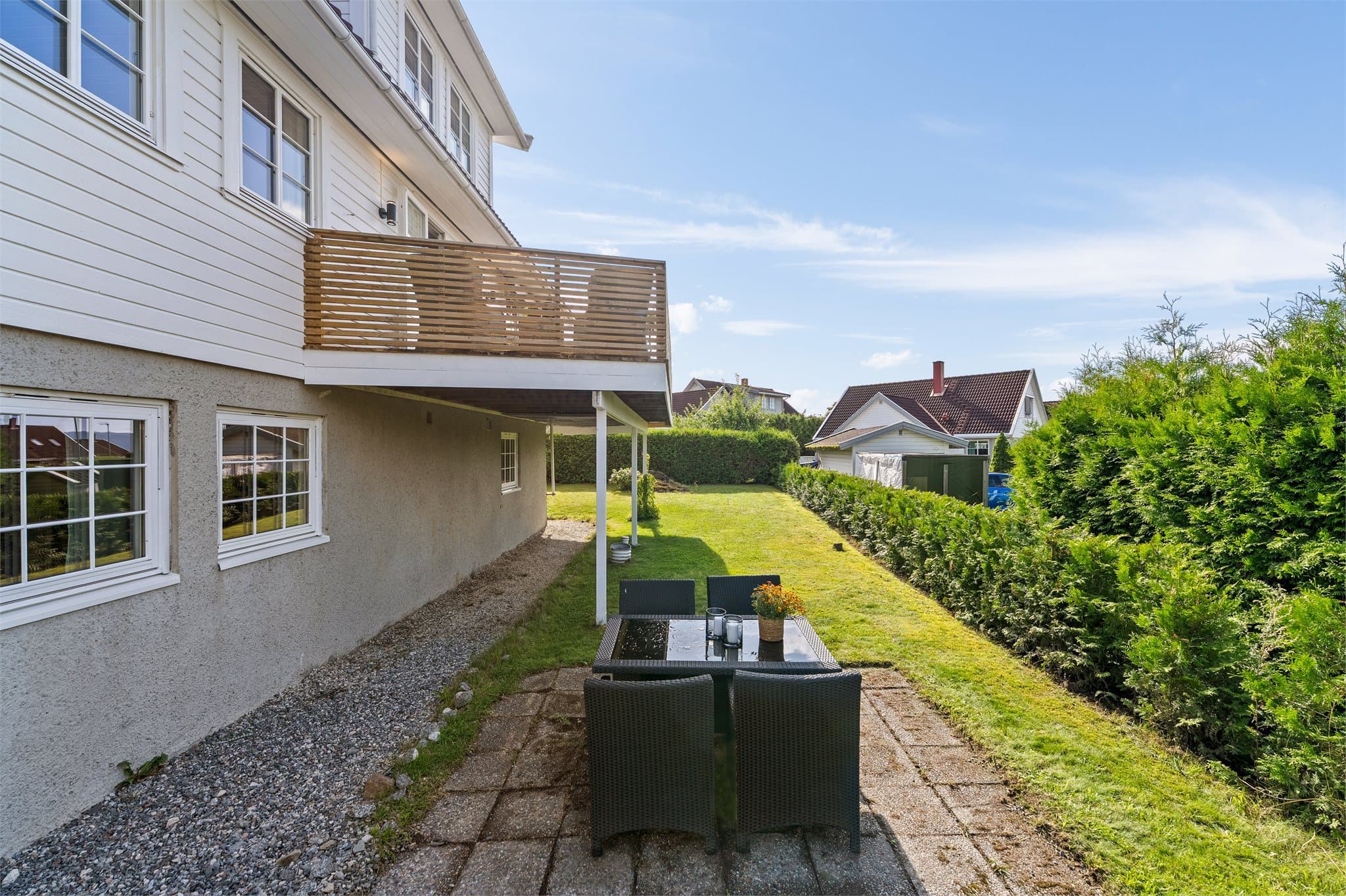 Det er en hellelagt uteplass og gruslagt stikkvei bort til inngangsdøren til sokkeletasjen.